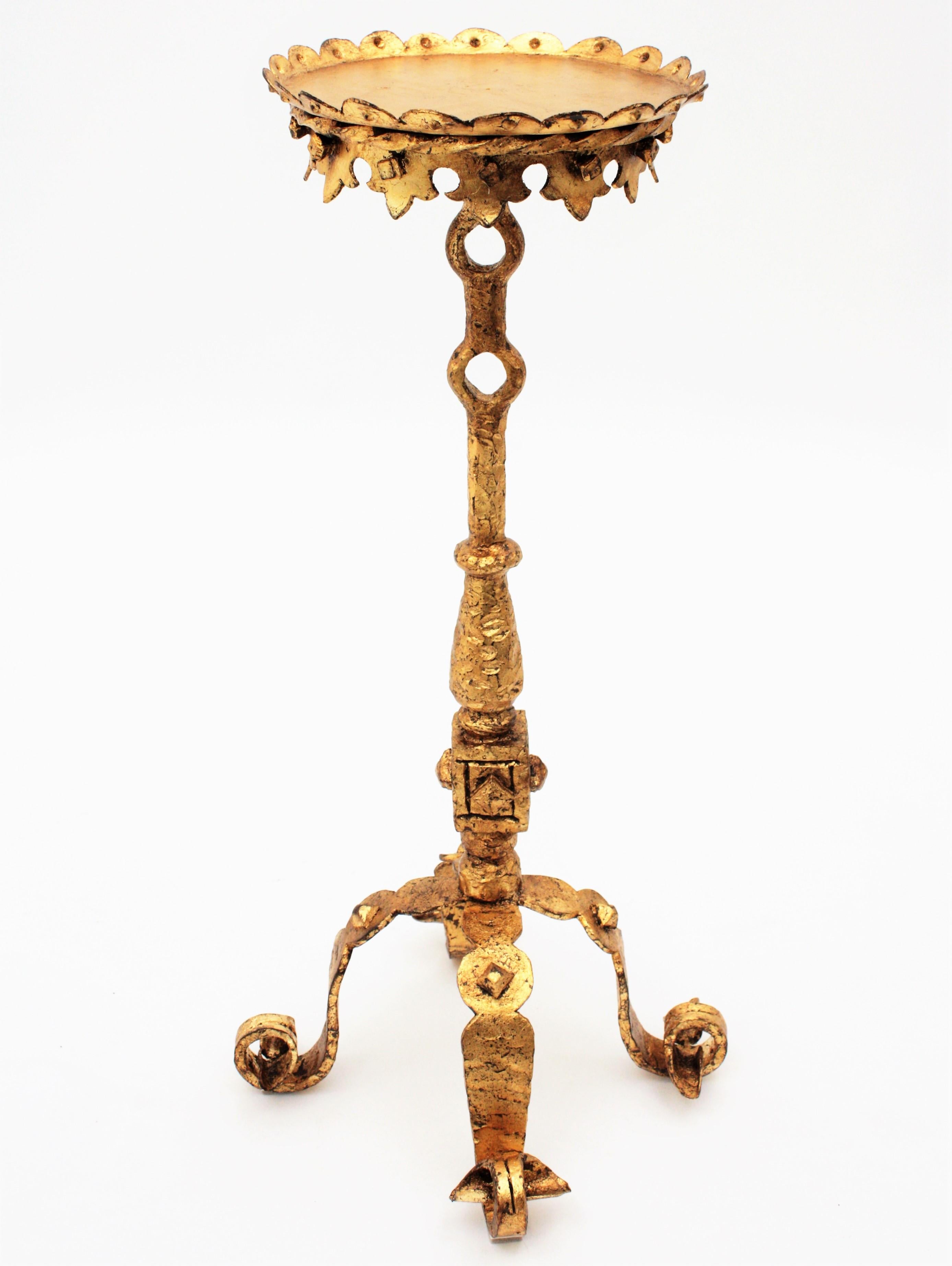 Unusual hand-hammered iron gold leaf gilded Gothic style side table, end table or stand with scroll motifs, Spain, 1920s.
This richly decorated gueridon stands on a four feet scrolled base, it has an scalloped round top and it has beautiful hammered