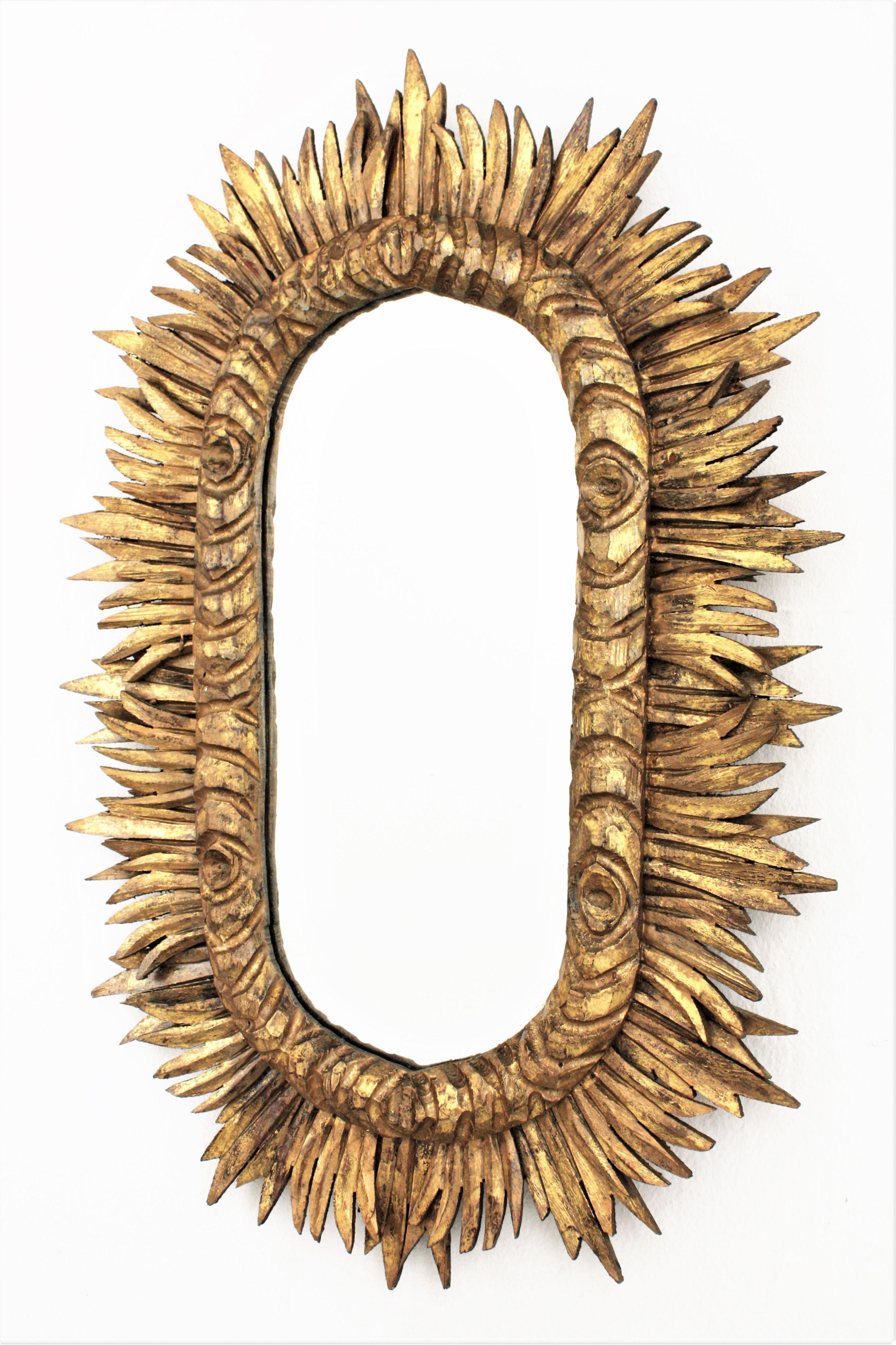 Impressive hand carved Baroque style oval shaped sunburst / starburst mirror. Spain, circa 1930s.
The frame is richly carved, it has two layers of beams and a beautiful gold leaf gilt covering the wood.
Excellent vintage condition and lovely