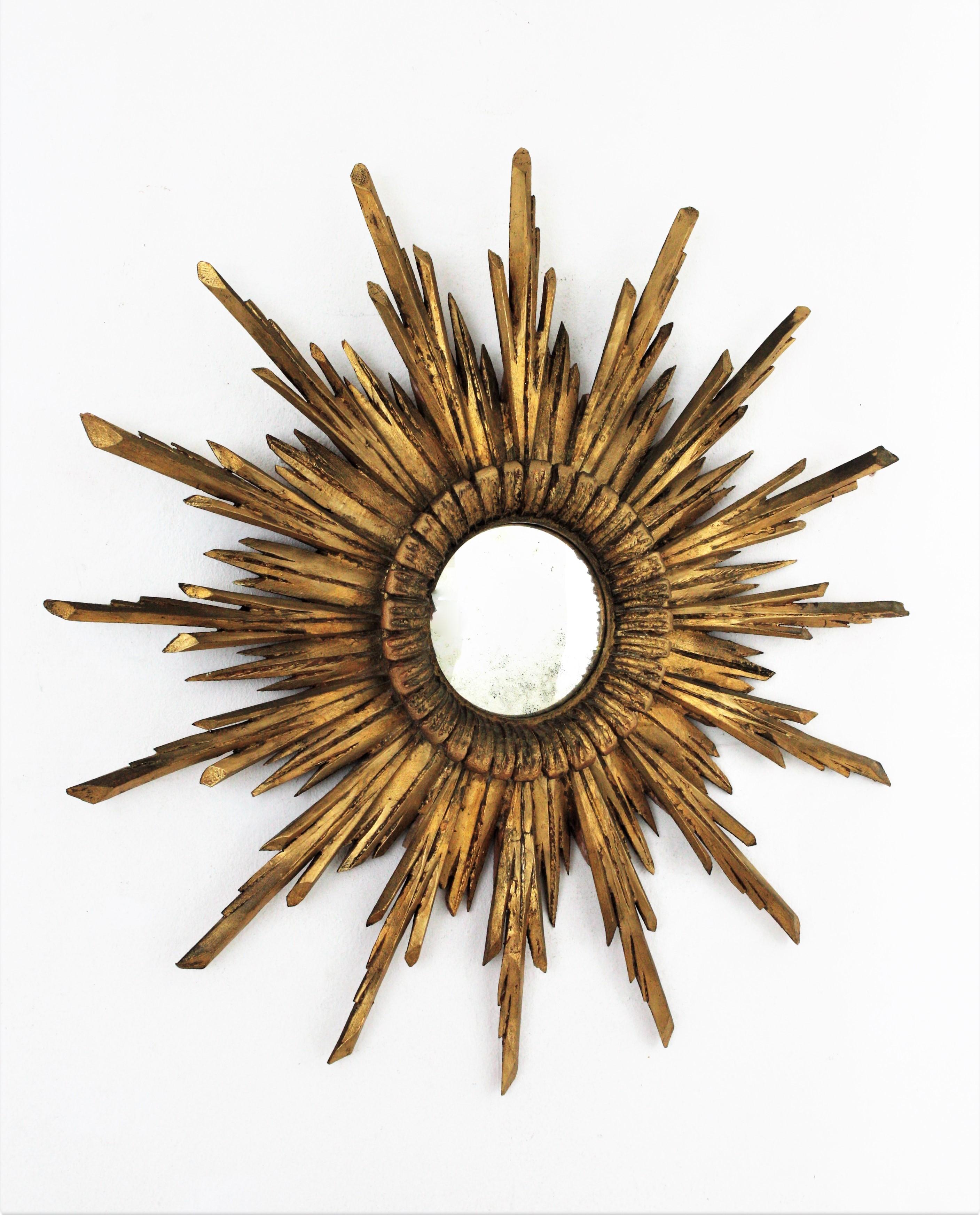 Impressive hand carved giltwood Baroque style sunburst / starburst mirror. Spain, circa 1930s.
The frame of this wall mirror is richly carved, it has two layers of beams in different sizes and a beautiful gold leaf gilt covering the wood.
Excellent