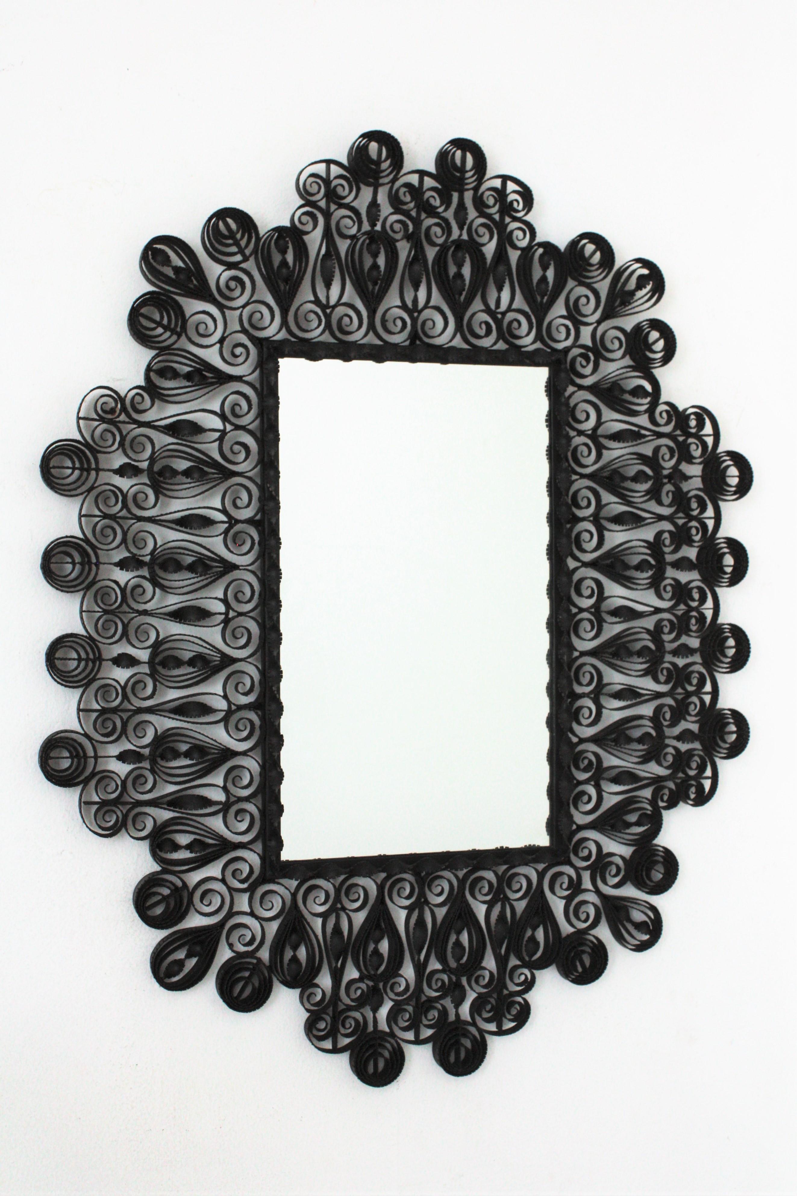 Impressive ornamented scrolled and twisted wrought iron rectangular mirror with Gothic style accents. Spain, 1940s.
This handcrafted mirror was manufactured in Spain at the Mid-Century Modern period. The frame is heavily decorated with hand-hammered