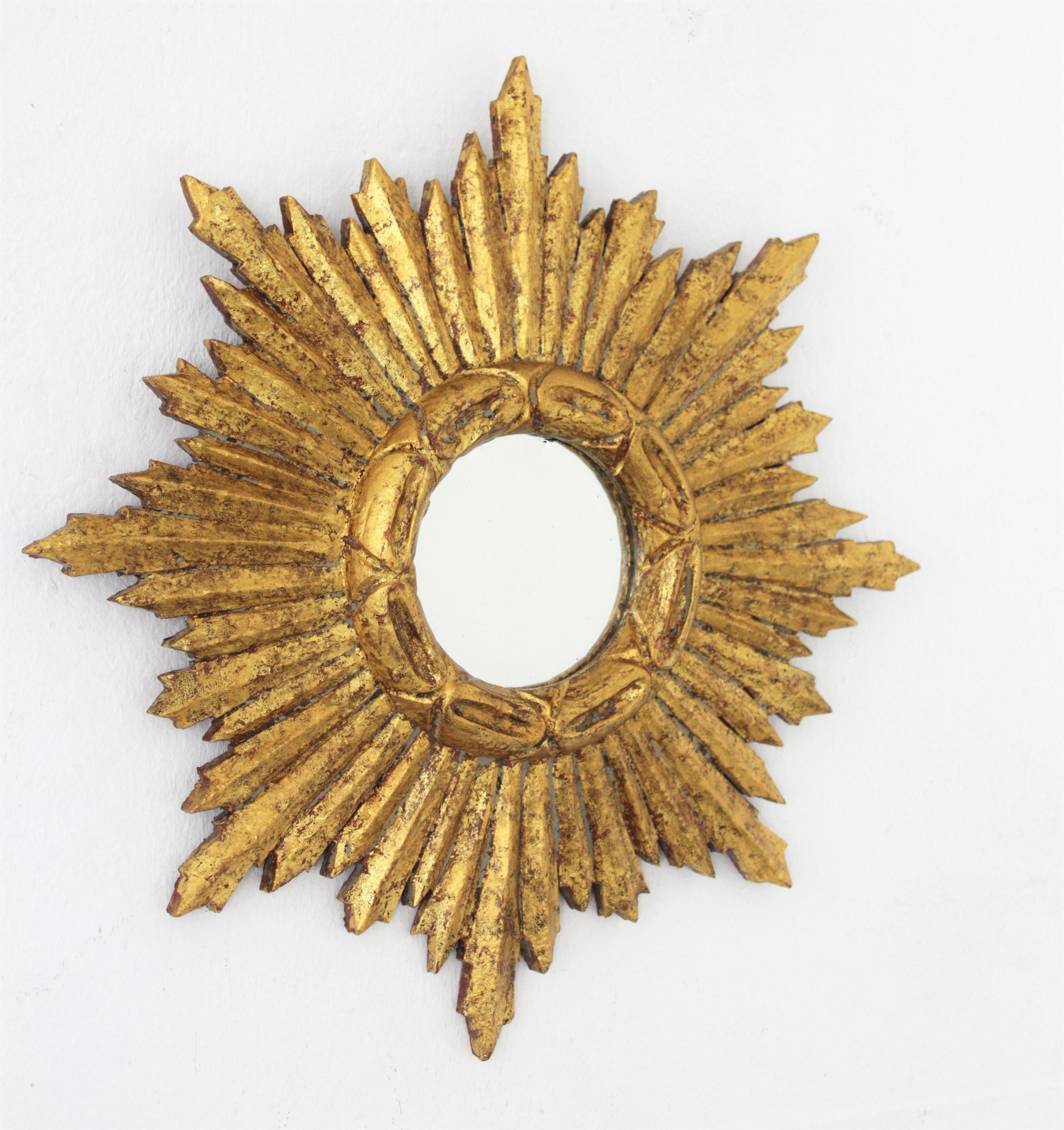 Lovely Baroque style small sized giltwood sunburst mirror with gold leaf finish. Interesting patina, beautiful to place it alone or with other sunburst mirrors creating a wall composition with more small sized sunburst mirrors, Spain, 1950s.