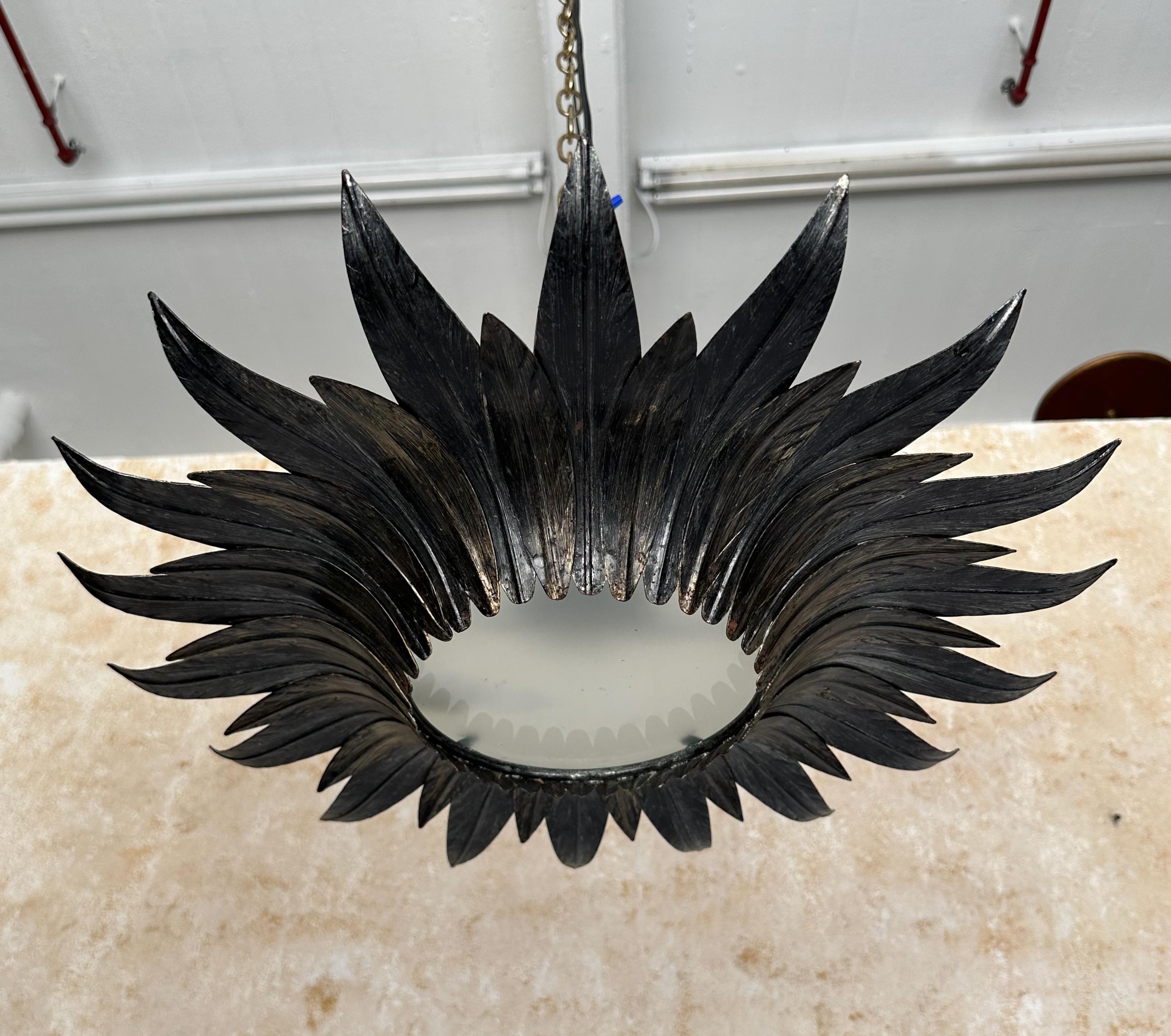 Cet élégant plafonnier espagnol en métal des années 1950 présente une alternance de grandes et de petites feuilles qui se chevauchent et entourent un centre en verre dépoli et s'enroulent gracieusement vers le haut. La riche finition dorée foncée