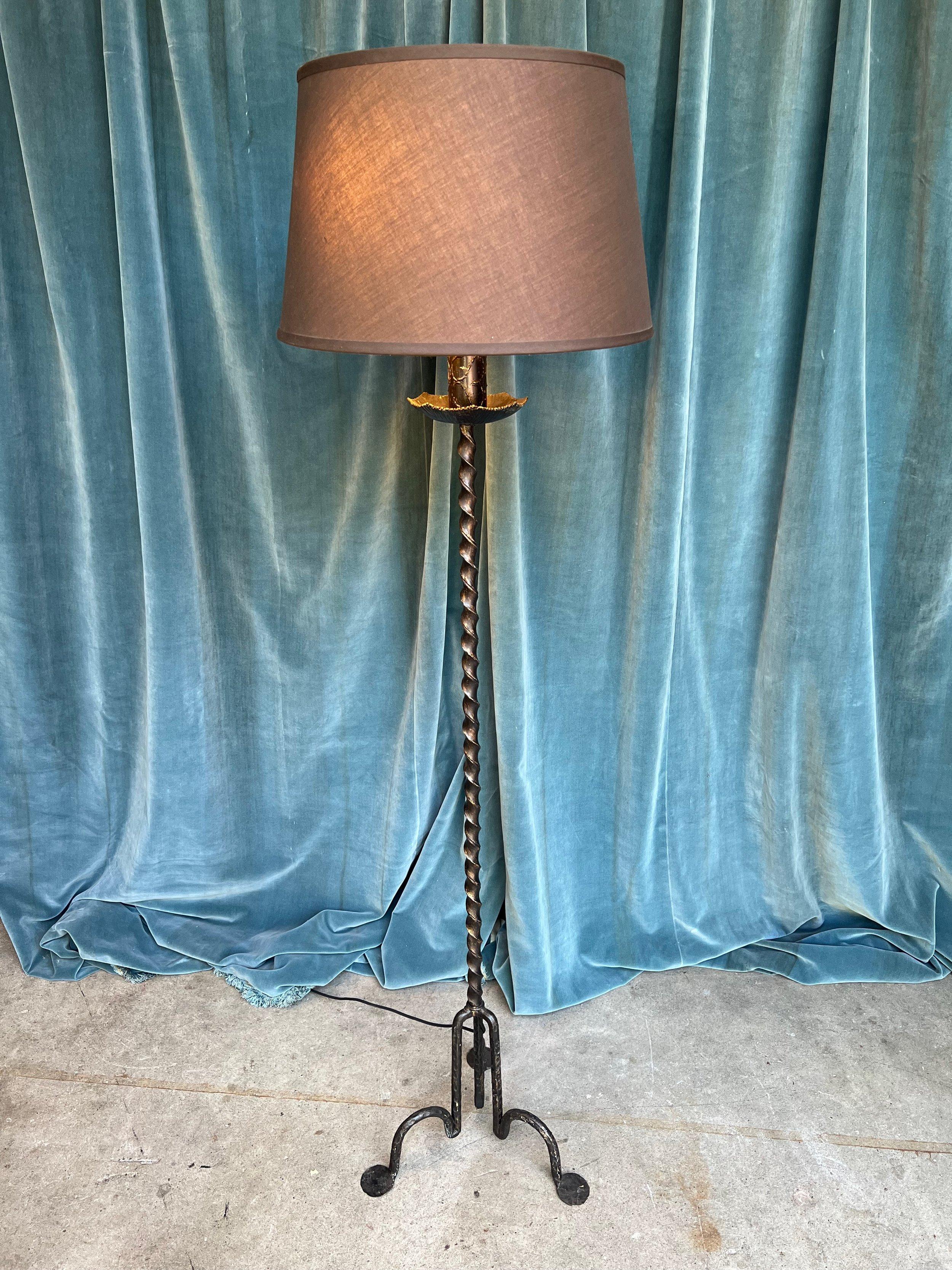 An unusual 1950s Spanish black painted wrought iron floor lamp in a captivating modernist style. The twisted central stem is mounted on a geometric tripod base with solid, pronounced feet, reflecting the exquisite craftsmanship and artistry of the
