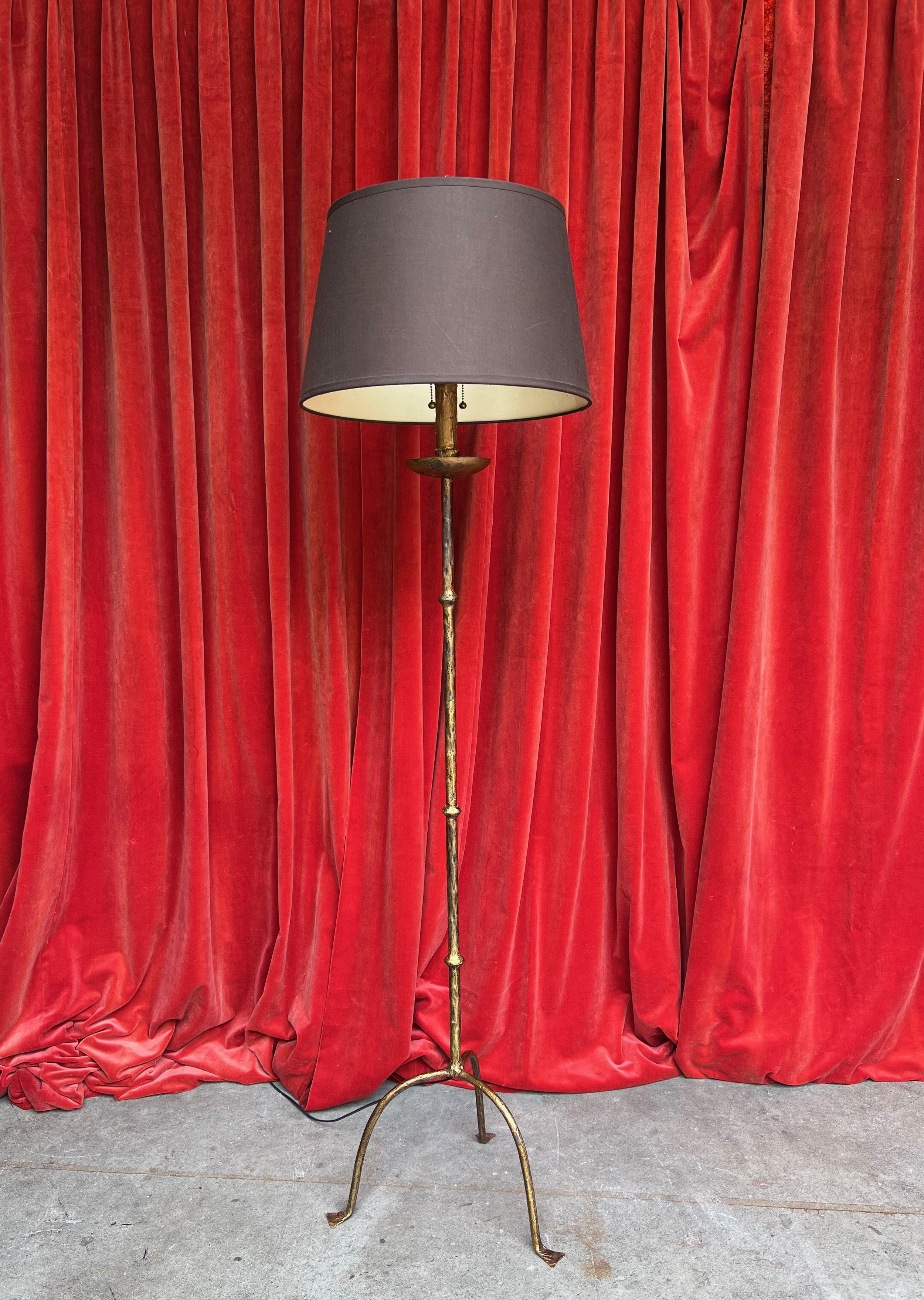 An elegant Spanish gilt iron floor lamp from the 1950s, featuring a striking wrought iron design on an elongated tripod base with a rich gold finish. The central stem displays three understated spherical details, enhancing its aesthetic appeal. The
