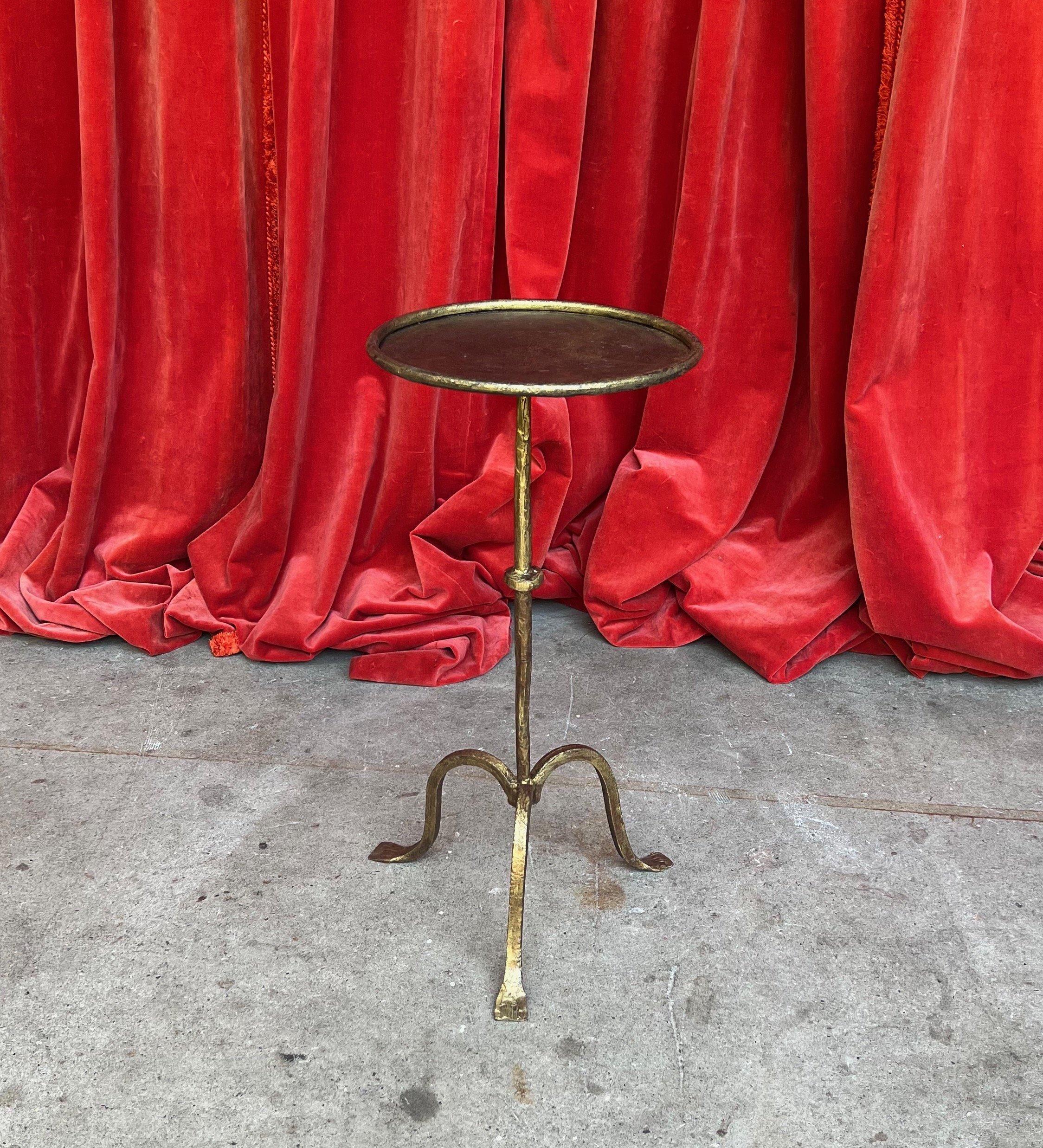 A simple yet enchanting Spanish gilt iron martini table from the 1950s featuring the original hand-applied gold finish with darker undertones, resulting in a rich and unique appearance. The elegant drinks table boasts a distinctive tripod base with