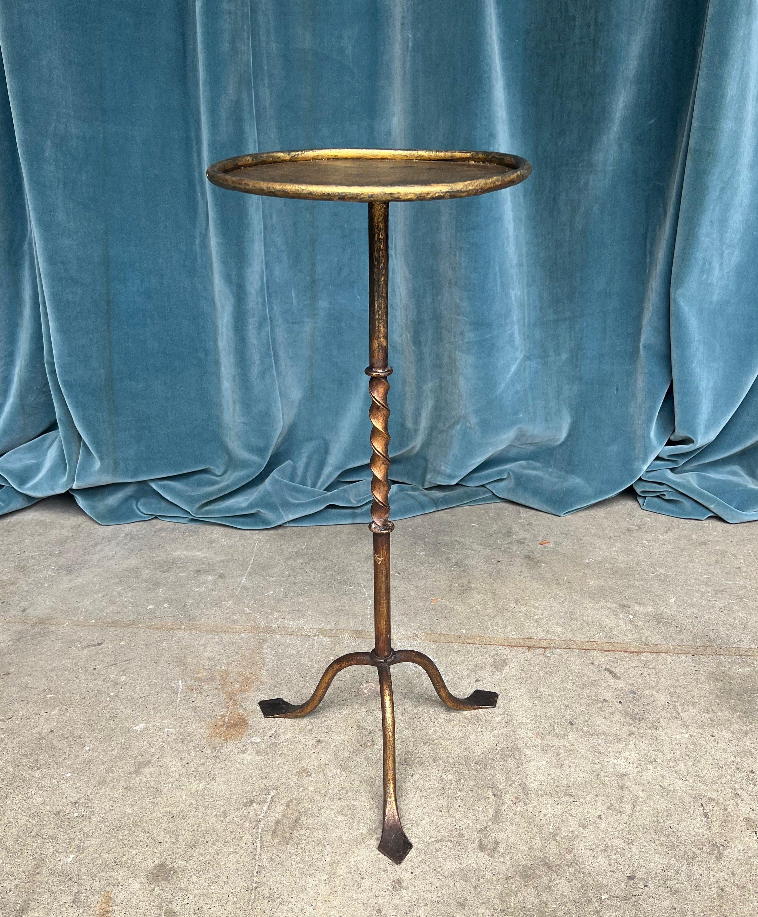 An elegant gilt iron martini table with rich hand applied gold patina over a darker black undercoat. Dating back to the 1950s, these drinks tables were highly popular in Spain and continue to captivate with their timeless charm. This delightful