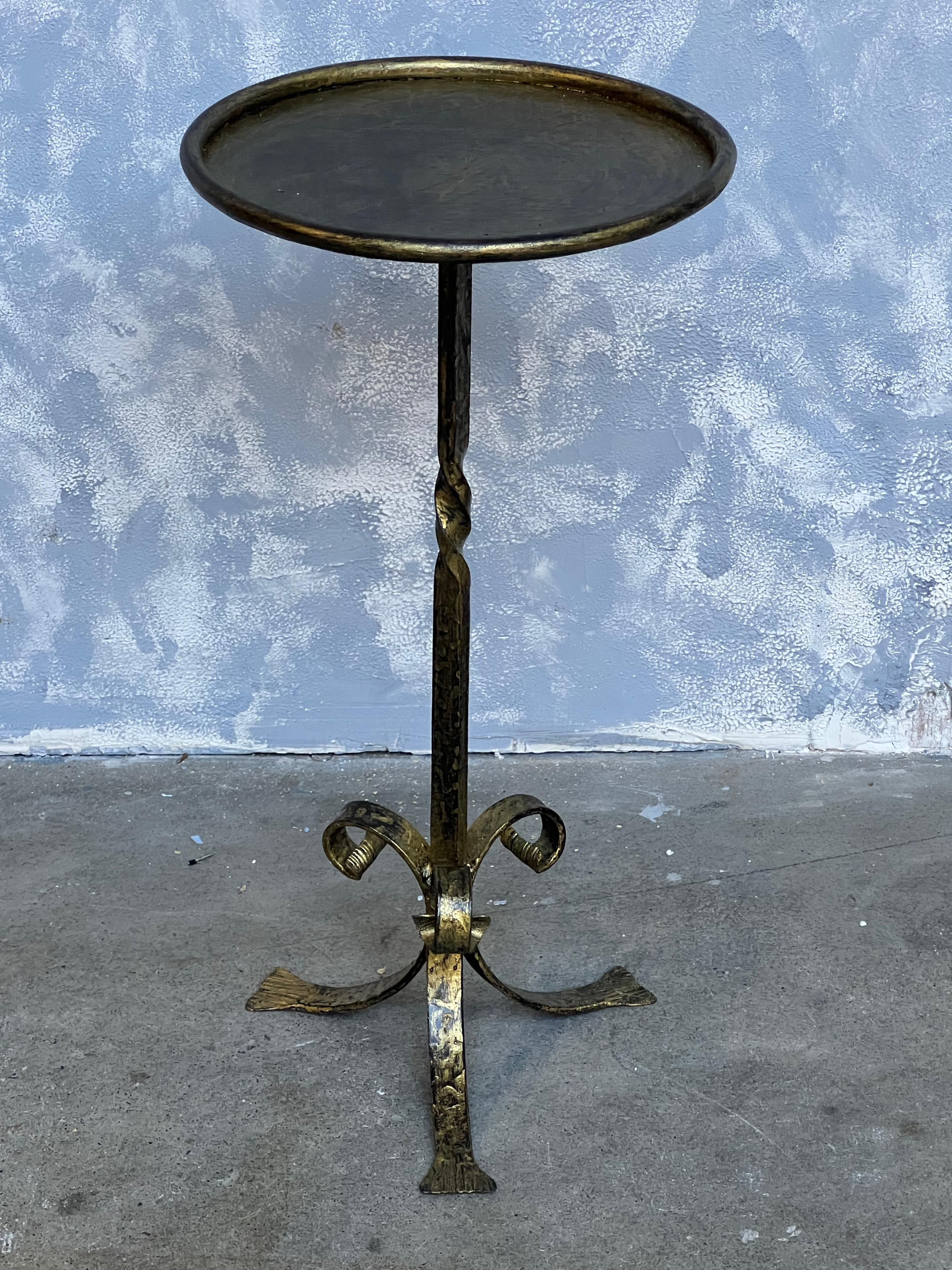 A small gilt iron side table that is perfect as a drinks table that can be moved around as needed. The hand patinated gilt finish has just the right amount of gold over a darker black undercoat to add texture and dimension to show off the age of the