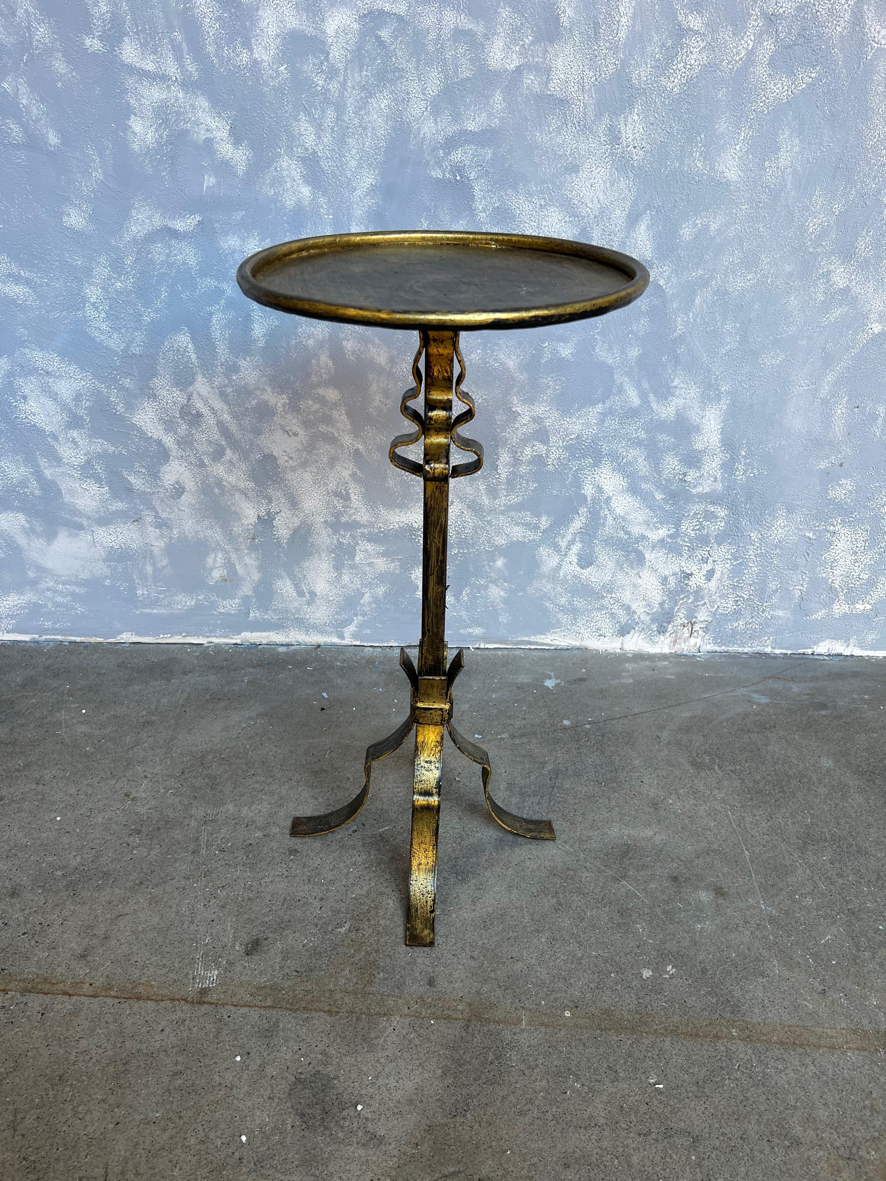 This interesting and ornate small gilt iron side table is perfect for holding a drink or a cup of coffee. Its hand-patinated gilt finish features just the right amount of gold over a darker black undercoat, adding texture and dimension to showcase