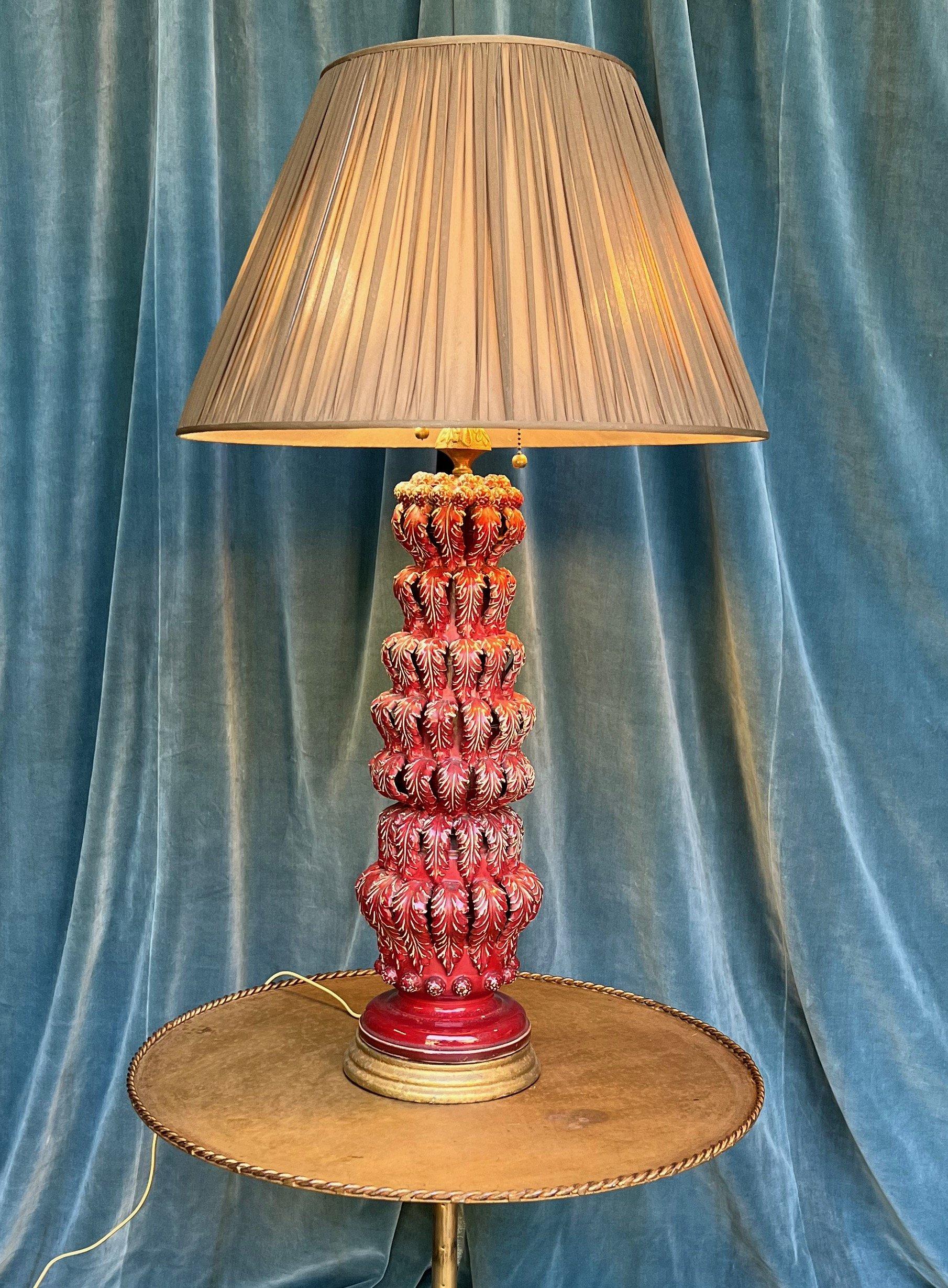 This elegant Spanish deep red glazed ceramic table lamp from the 1950s features stylized draped leaf decorations. Mounted on a giltwood base, this lamp exudes sophistication and charm, especially in its unique deep red color with white highlights.
