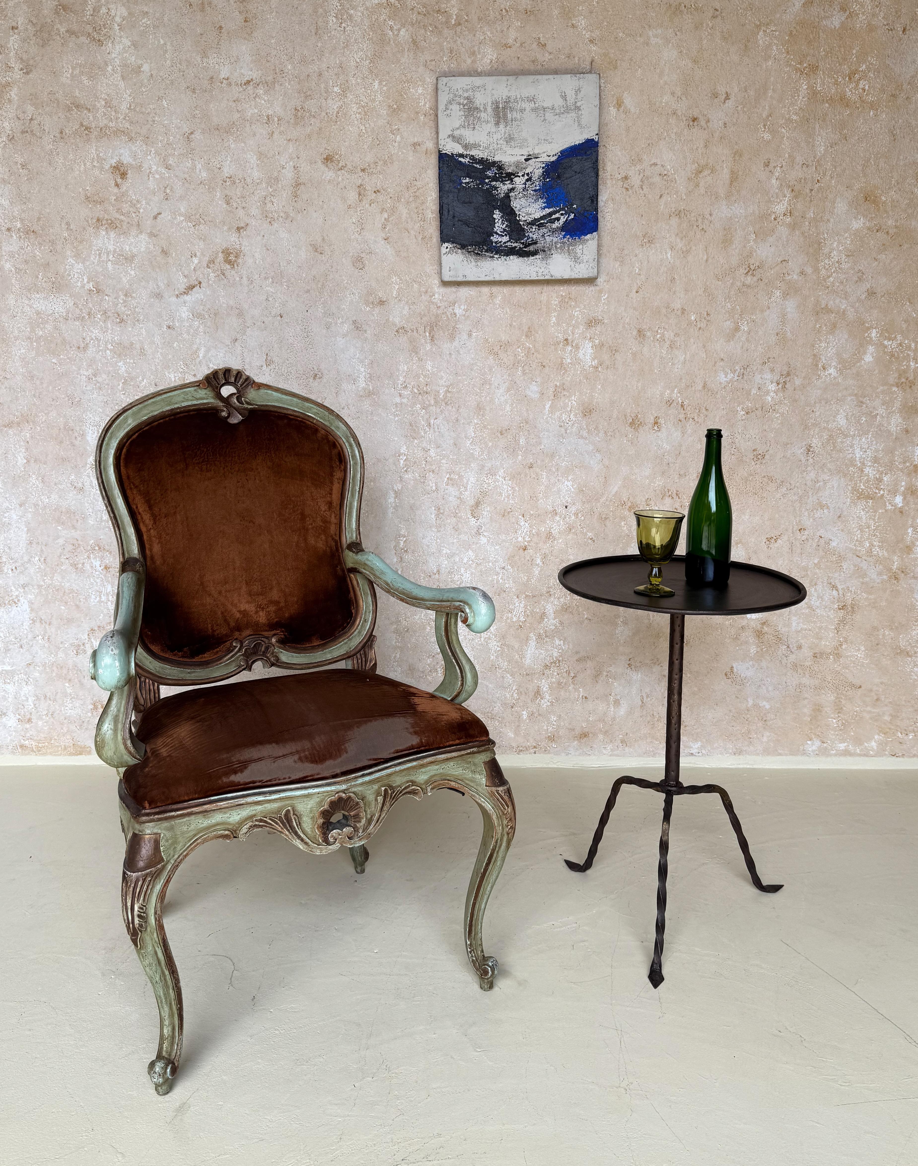 Esta elegante mesa auxiliar española vintage de la década de 1950 presenta una construcción de hierro forjado a mano, que ejemplifica la artesanía y el diseño atemporal. El tablero redondo está bordeado por un sutil labio enrollado, a la vez