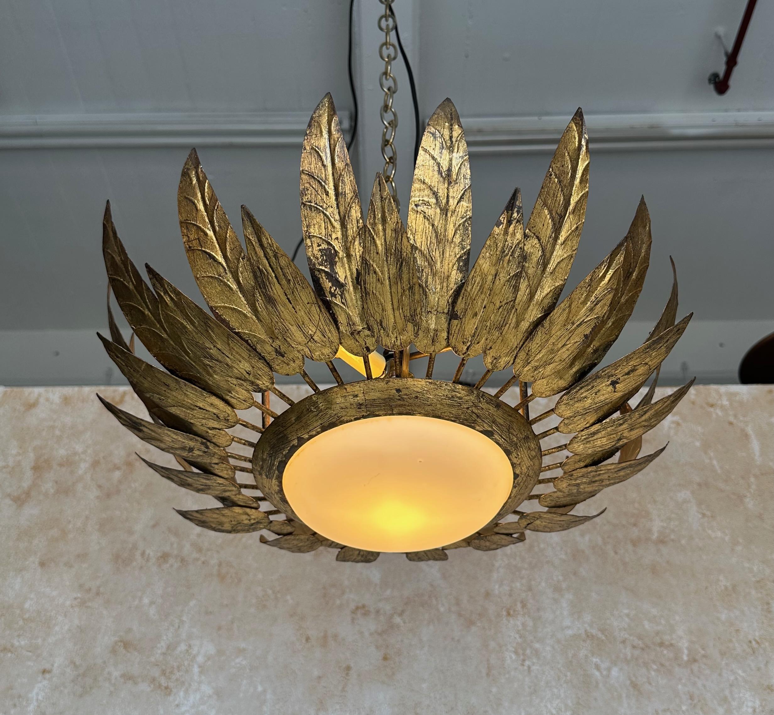 Questo brillante apparecchio da soffitto a incasso in metallo dorato, risalente agli anni '60, è un pezzo di artigianato spagnolo davvero straordinario. La solida cornice racchiude un globo opalino bianco convesso e vanta un doppio ordine di foglie