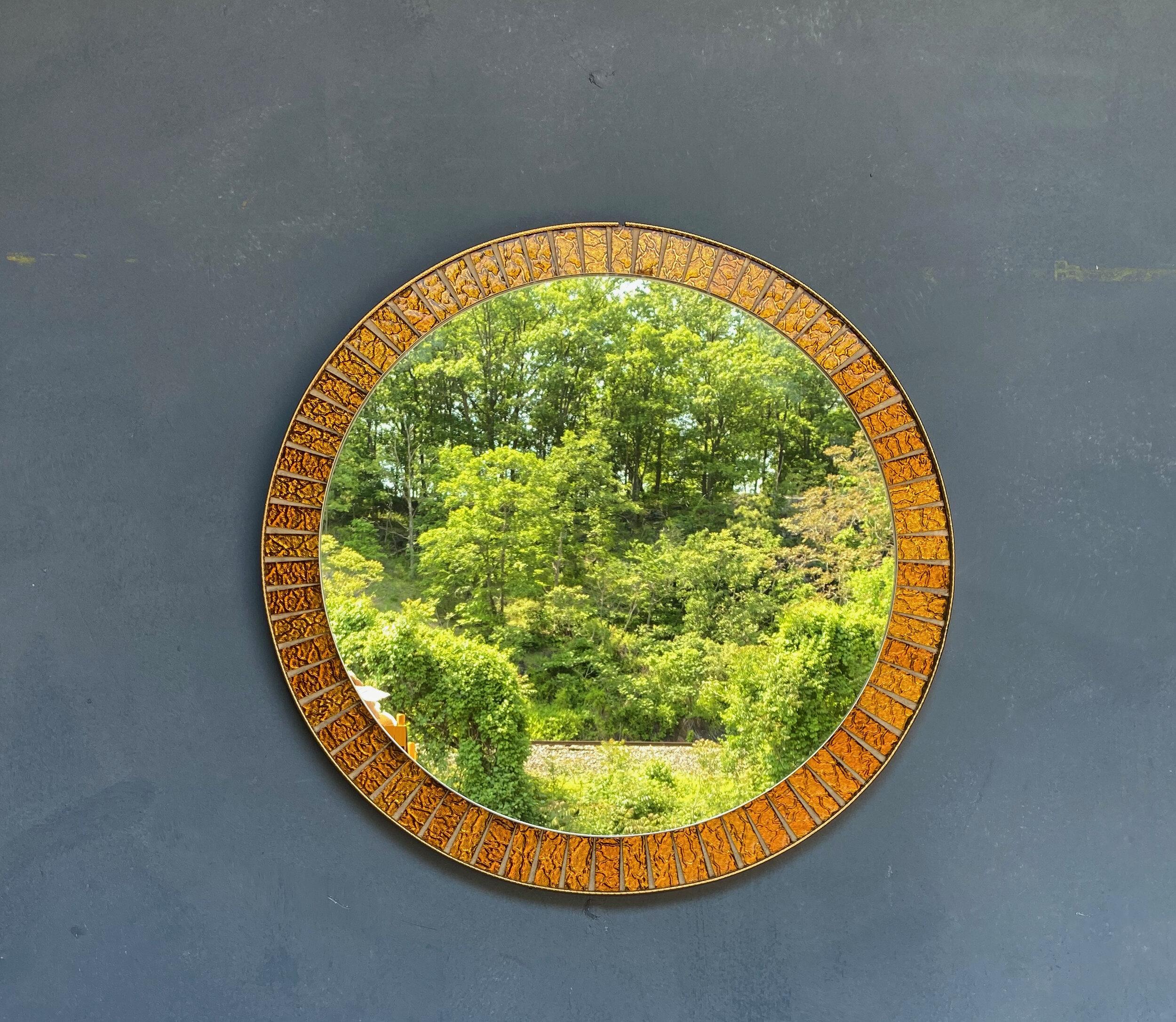 This round Spanish 1960s mirror features a brass enclosed frame surrounding alternating gold metallic sections with radiating brass dividers.  In very good vintage condition, and with a diameter of 23 inches, this eye-catching mid century mirror is