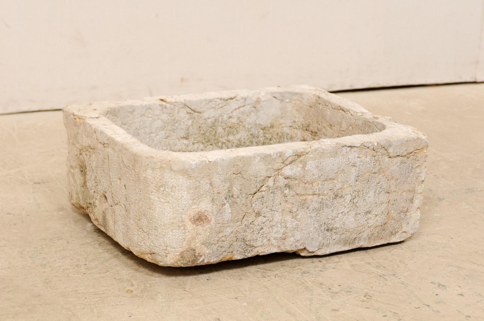 A Spanish carved limestone basin from the 19th century. This antique vessel from Spain, with it's rectangular shape, has been hand carved out of a single piece of limestone, having a nicely textured surface. There are two small drain holes at the