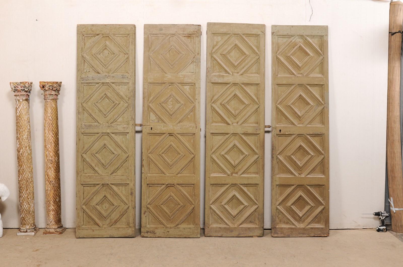 A Spanish set of two pair of raised-paneled doors from the 19th century. These antique doors from Spain, consisting of two pairs (four total doors), each feature a four stacked and raised panel design with large diamond shape carvings within the