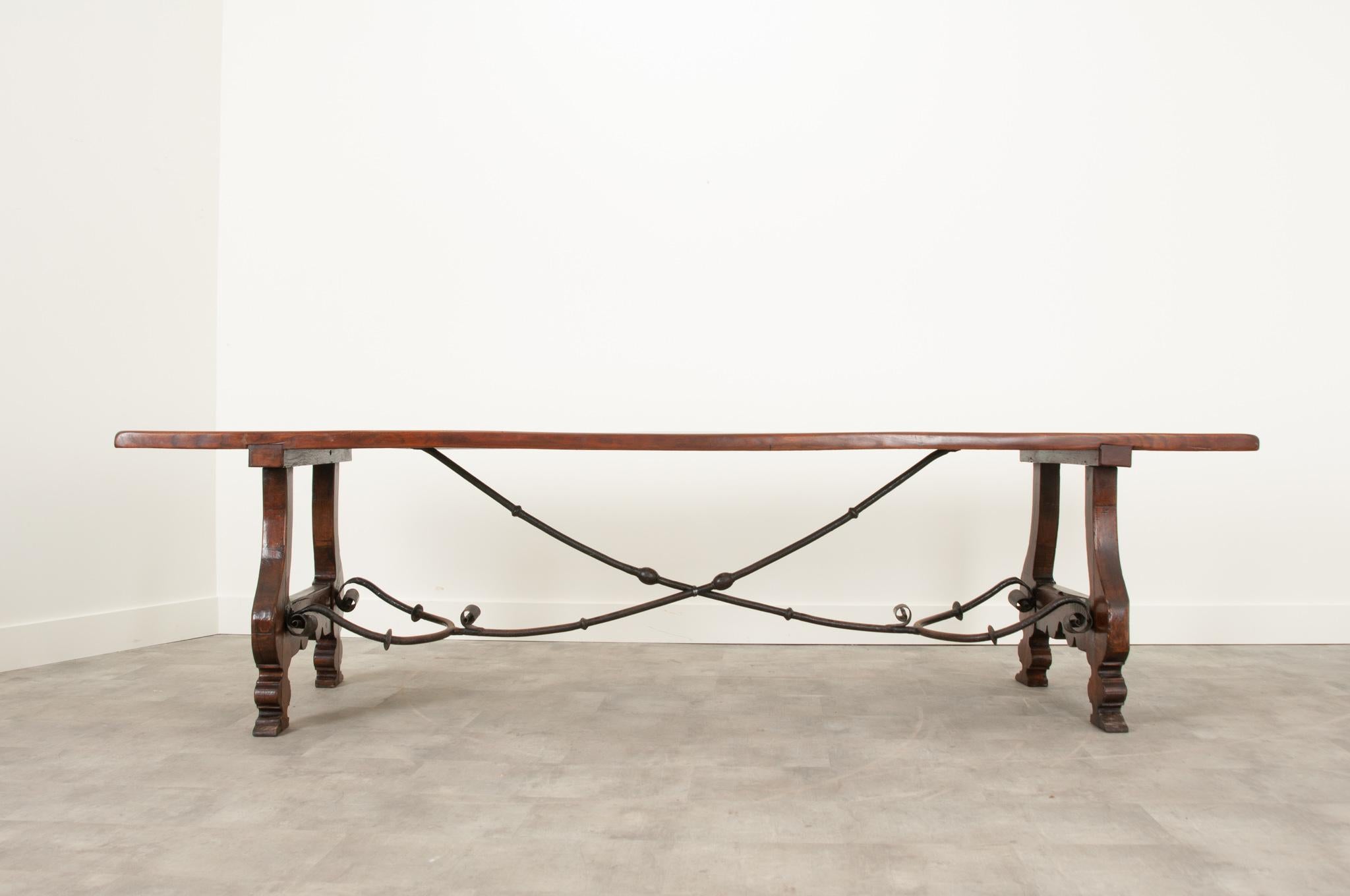 An impressive and long Spanish dining table is made of solid oak with a hand forged iron scrolled stretcher. The top is 1 3/4