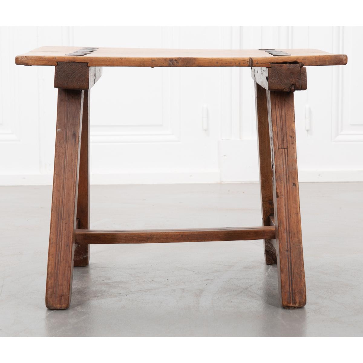 Simple but gorgeous antique table, circa 1840. The wood top is held to the frame with large, hand forged, iron nails. The trestle-style frame itself has mortise and Tenon joints held together with wooden pegs. Exposed dovetail-like joinery adds