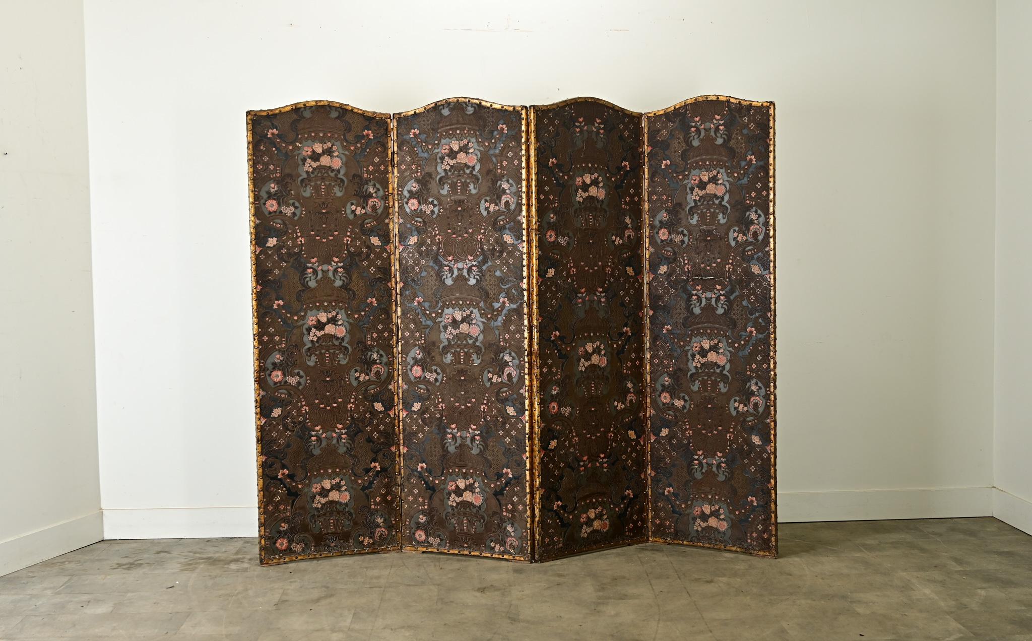 Magnifique paravent espagnol du XIXe siècle en cuir estampé de plus de deux mètres de haut, orné de motifs floraux et feuillus qui couvrent la surface de l'écran avec un grand effet. Les quatre panneaux reliés entre eux sont chacun couronnés d'une