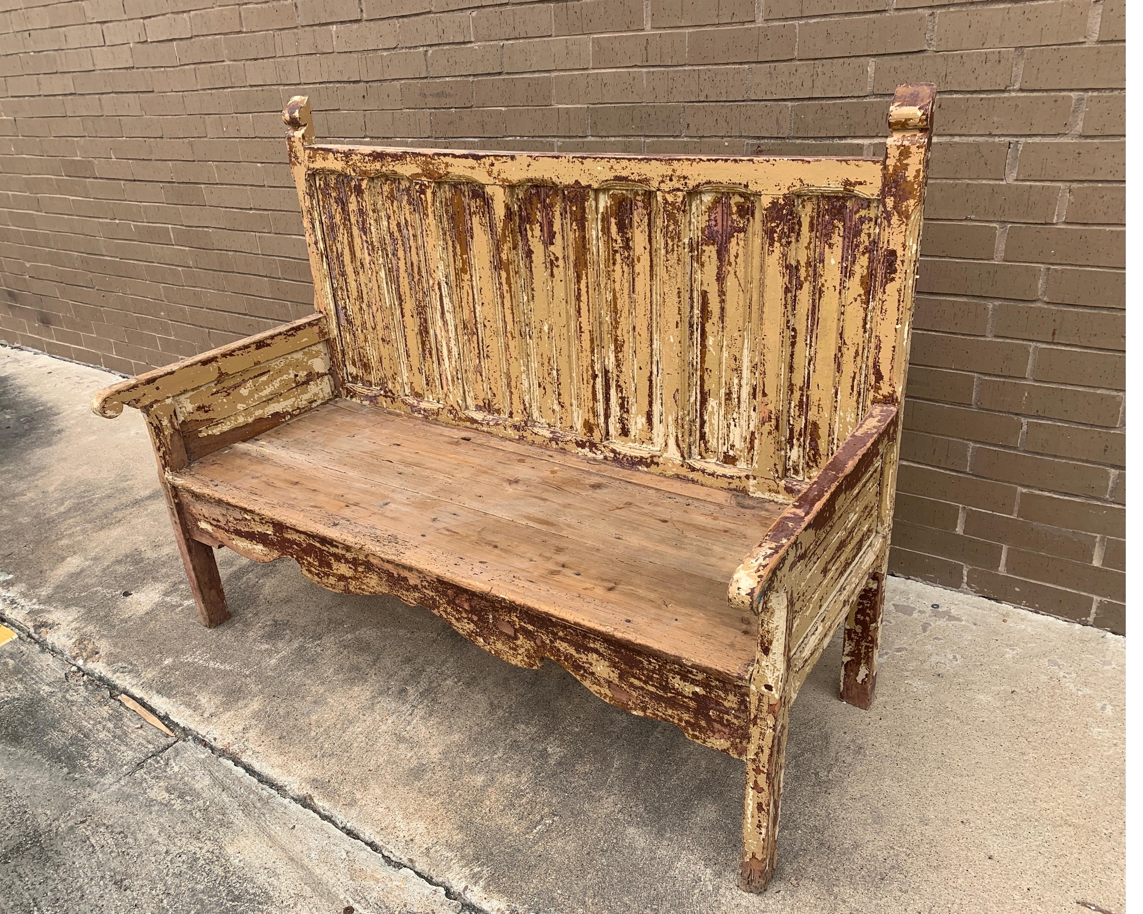 This Spanish bench has a high solid back and ton of character. It’s rustic and sturdy with layers of paint. It's great against a wall under a covered patio or inside the home in a hallway.