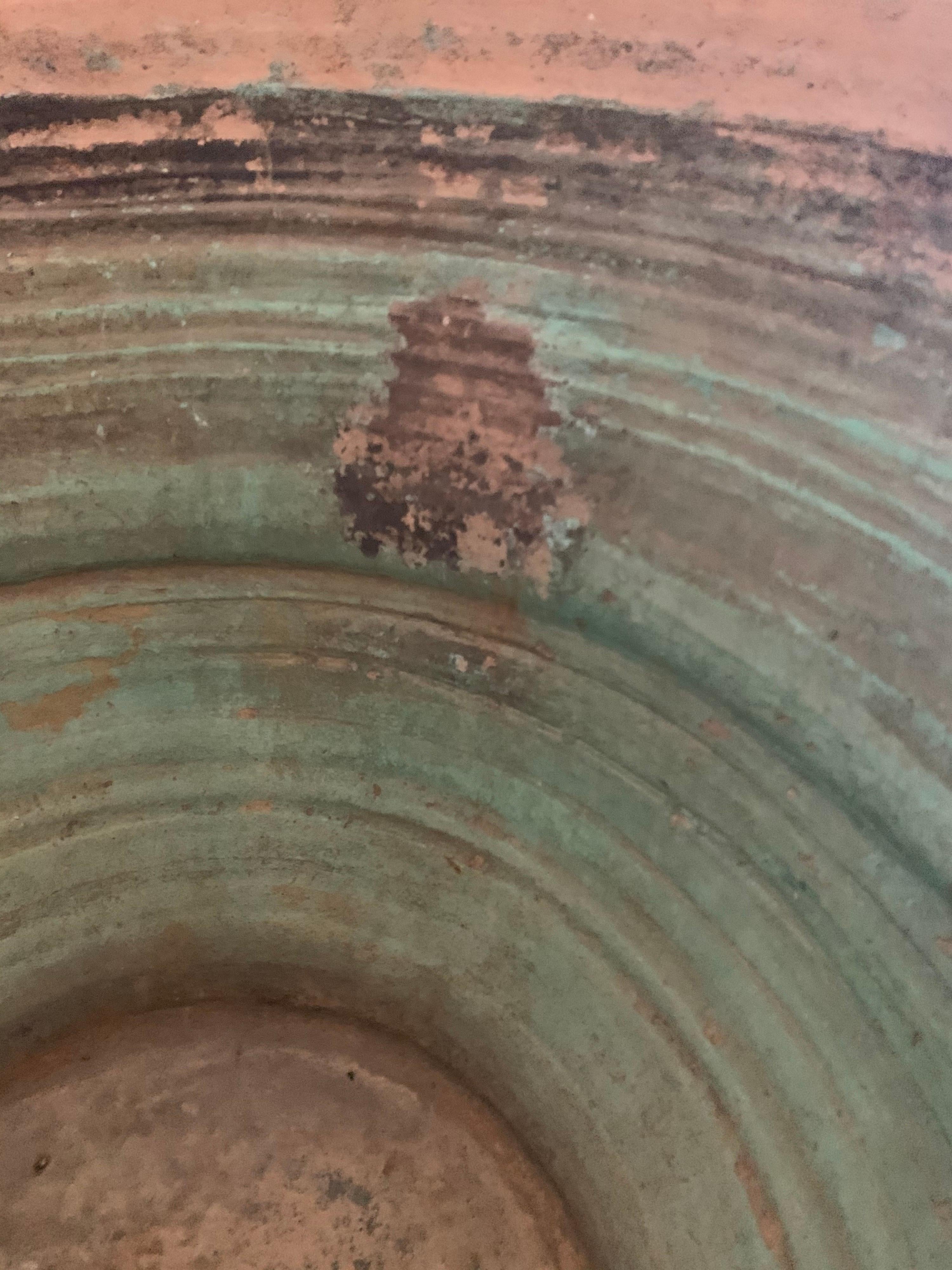 Large pot from Spain with green color inside and old staples on the exterior.