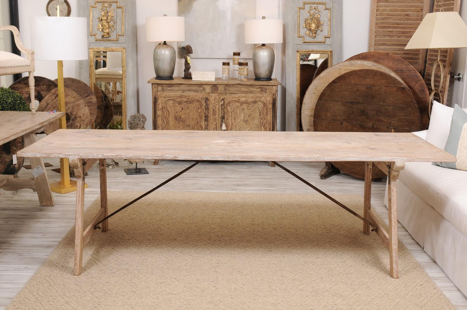 A Spanish Andalusian refinished long dining farm table from the 19th century with trestle base and iron stretcher. The clean and elegant lines of this old table caught our attention, and once we saw the graceful iron struts underneath, we were sold.