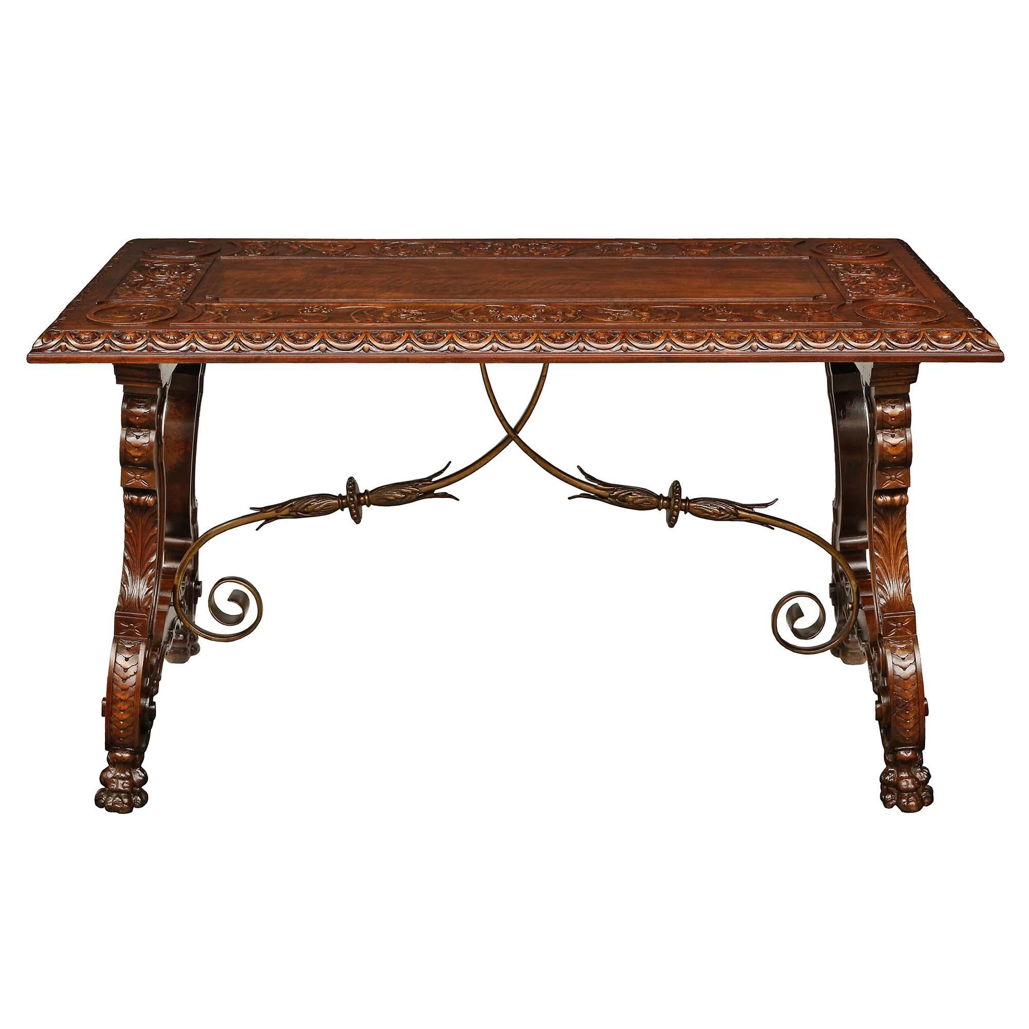 A handsome Spanish 19th century Renaissance st. walnut trestle table. The table is raised by four handsome richly carved paw feet below the impressive scrolling supports with finely carved floral patterns throughout. The striking iron scrolled