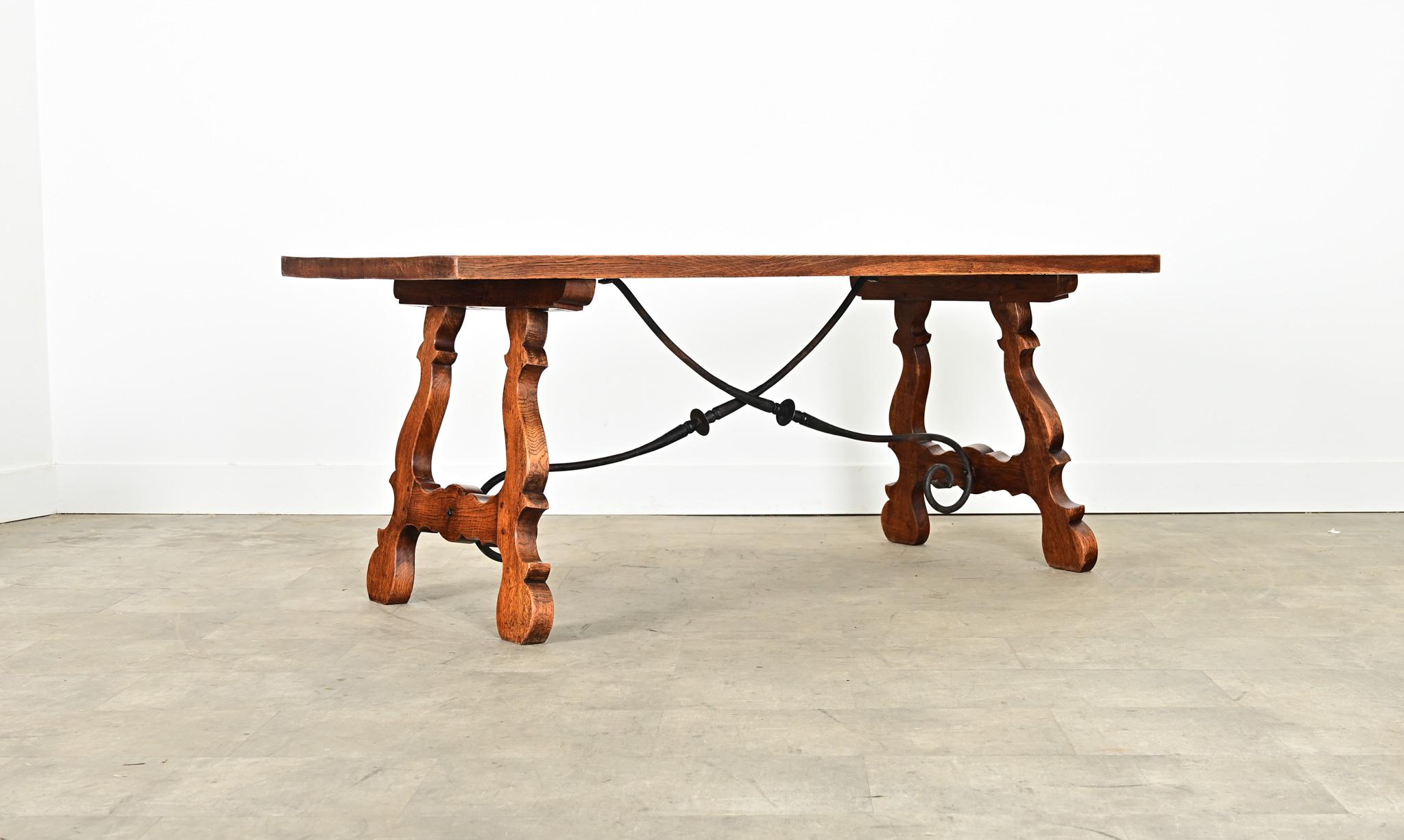 A multipurpose Spanish fratino table from the 19th century in handsome oak construction with stretchers of wrought-iron for dining, as a center table, or writing desk. Thick top planks are in remarkable condition, smooth and clear to appreciate the
