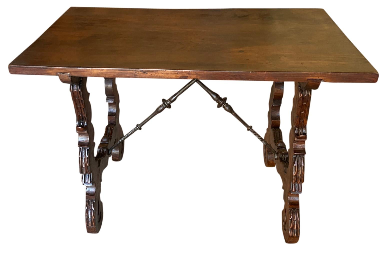 A very lovely 19th century Spanish Writing Table - Side Table soundly constructed from walnut and hand forged iron stretchers. Handsome carvings on the classical lyre shaped legs. The table has a wonderful solid board top. Wonderful patina.