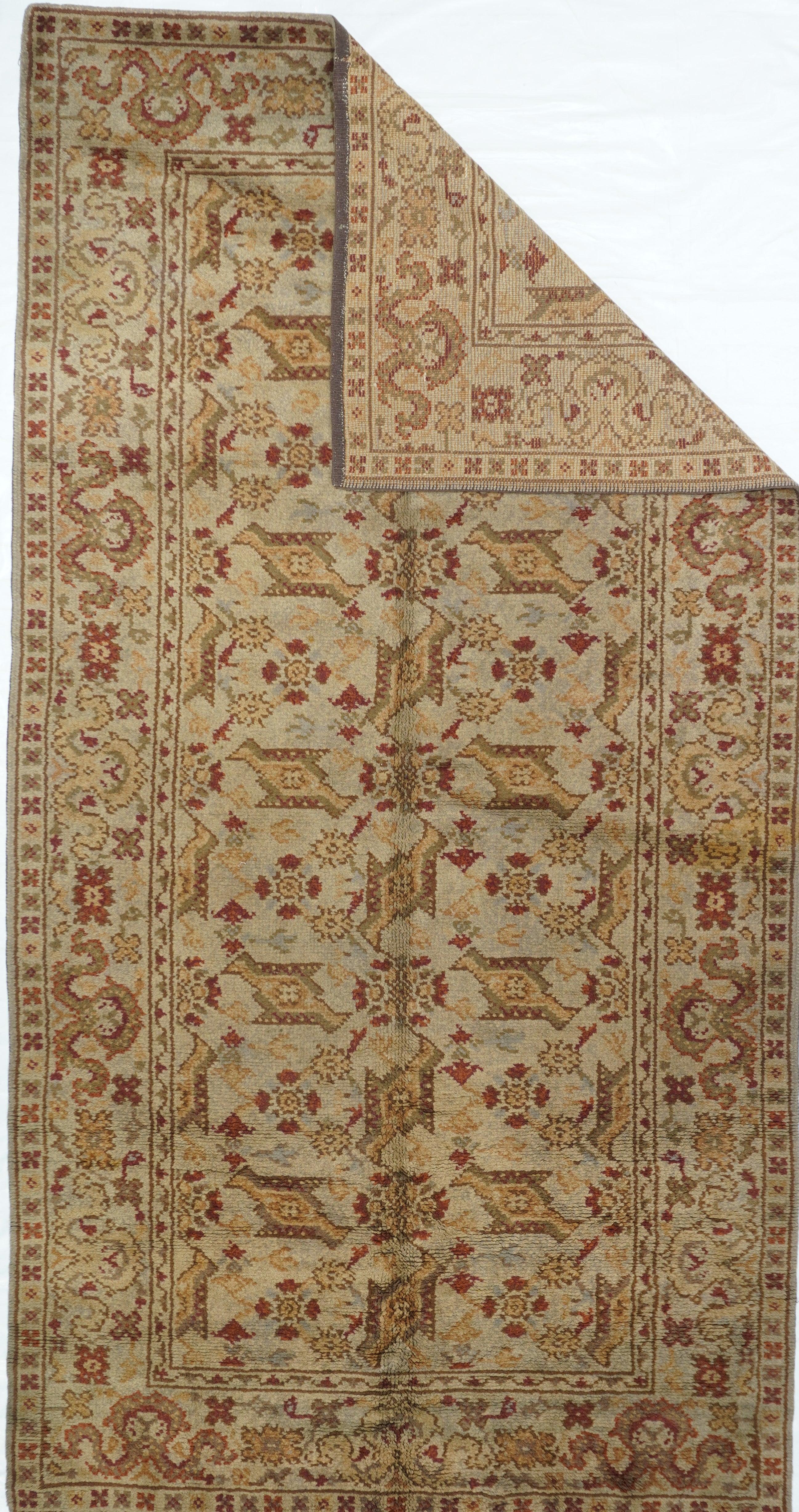 This modern copy of a 17th century Oushak “bird carpet” shows two columns of “bird” leaves around a central run of rosettes, on a straw-sand ground. Straw-sand border with cloud bands and rosettes. The “bird” pattern never really gores out of style