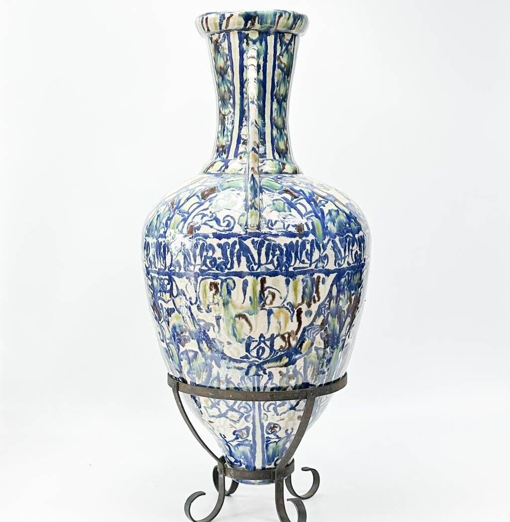  Vase à double anse Alhambra en poterie hispano-mauresque, vers 1900. Finition épaisse glacée et texturée, décor bleu et vert. Support en fer forgé.

Informations supplémentaires : 
Type : Vase en poterie
Poids approximatif, 25 lbs
Mesure environ