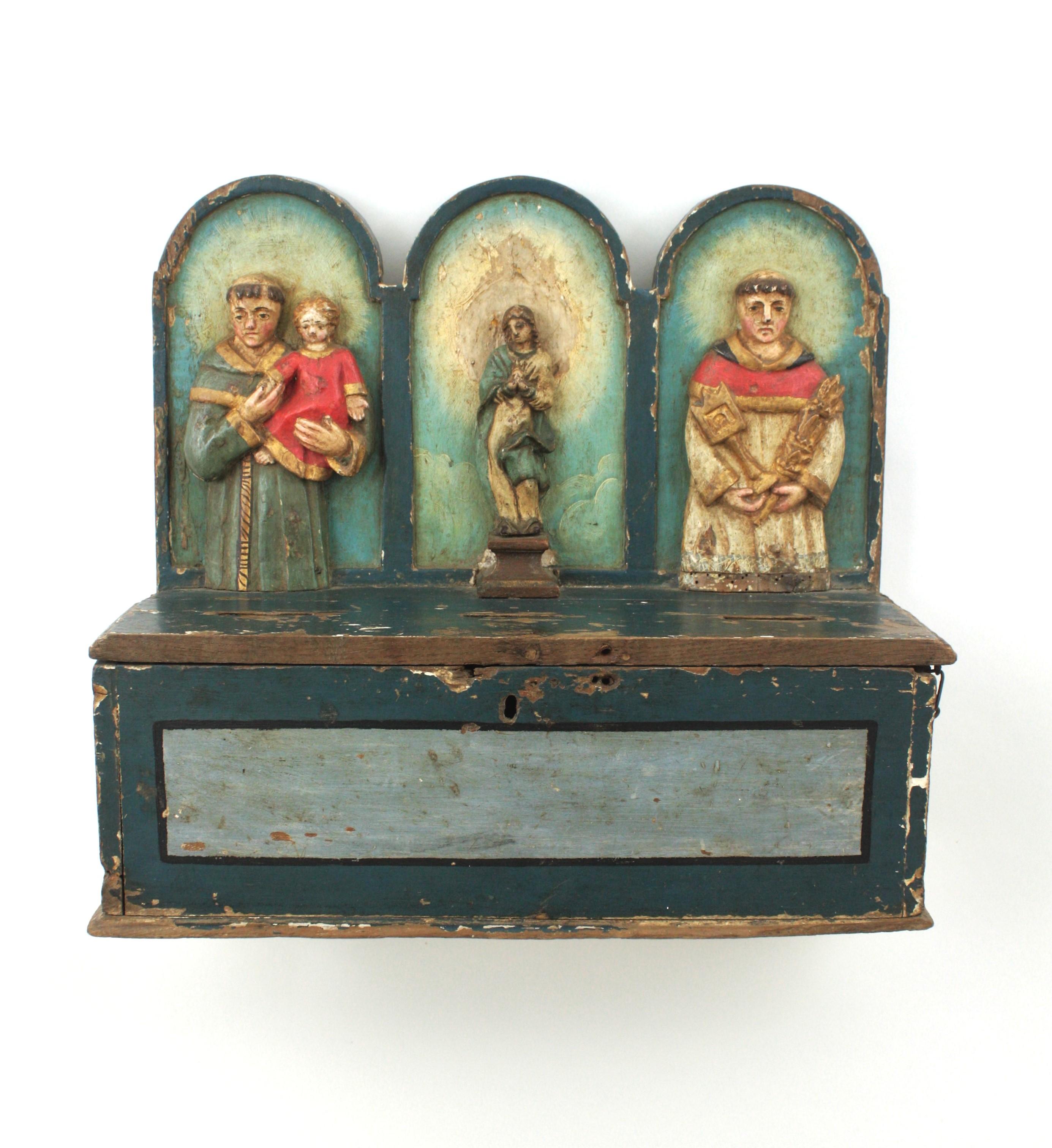 Caja de donativos / ofrendas de madera tallada y pintada a mano, España, siglo XVIII.
Hucha de madera tallada policromada para donativos de ofrendas de iglesias como decoración de pared.
Esta limosnera está hecha de madera de pino pintada en tonos