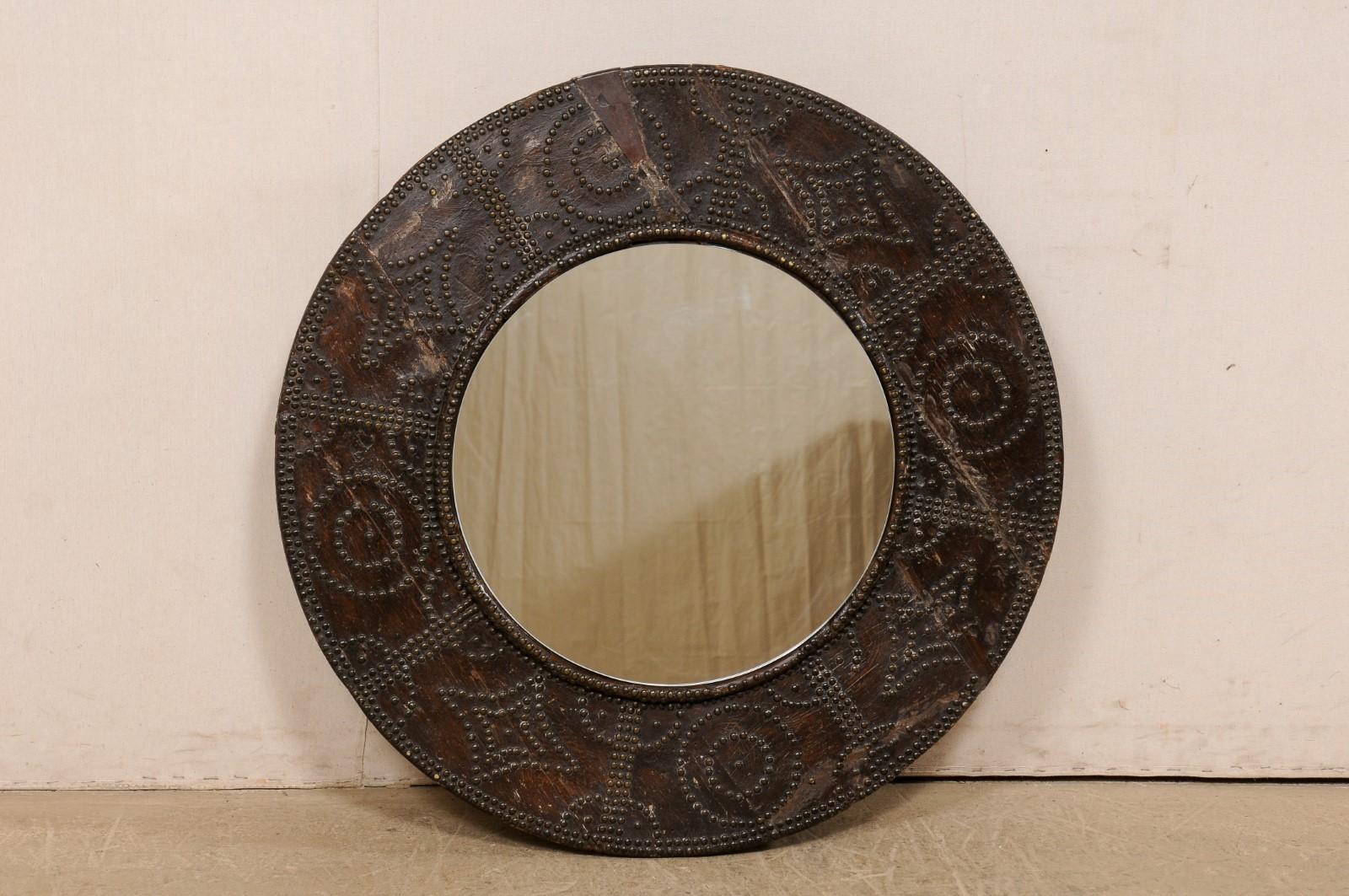 A Spanish mirror, with brazier surround from the turn of the 19th and 20th century. This unique circular mirror which has been custom fashioned with an antique Spanish wooden brazier (beautifully adorn with a nail-head design) as the surround, with