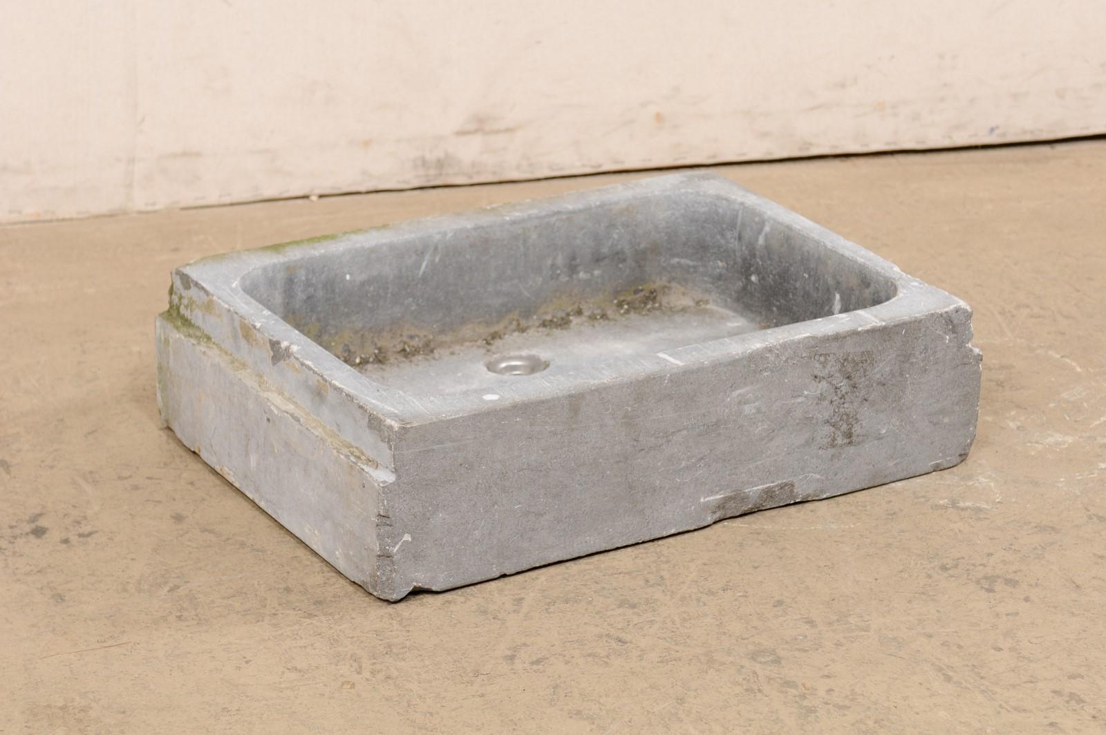 A Spanish carved-stone sink, with shallow basin, from the early 20th century. This antique hand-carved bluestone sink from Spain has an overall rectangular-shape, which houses a shallow, 5