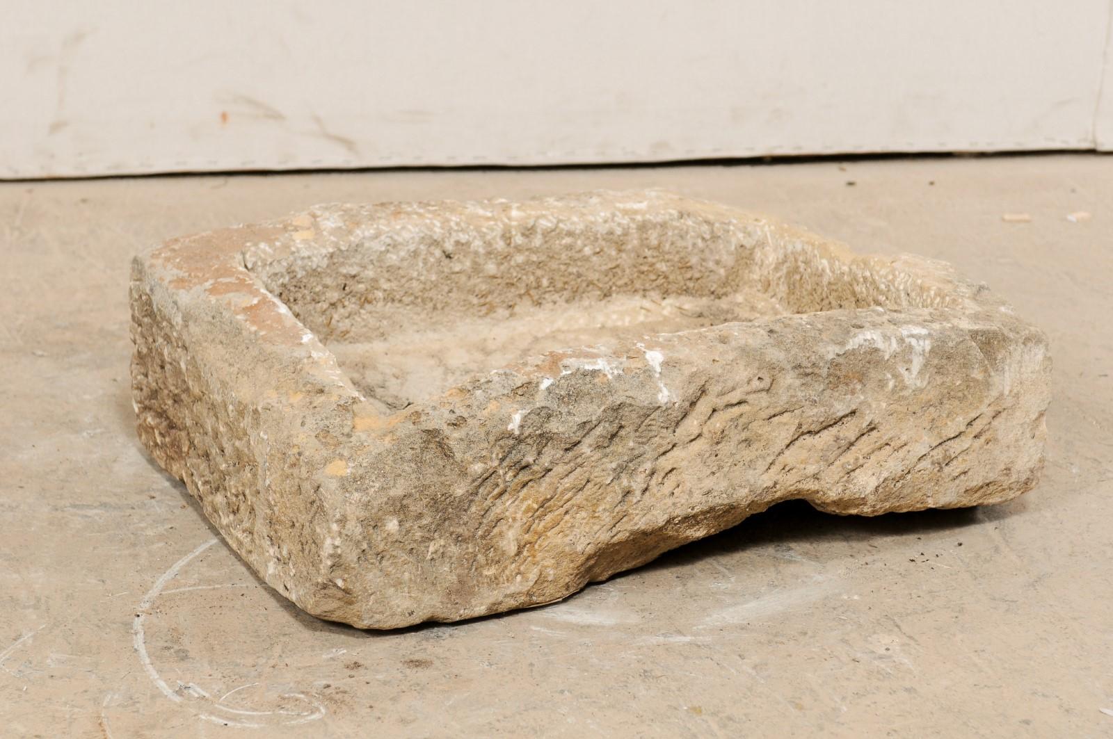 A Spanish carved-stone trough from the 19th century. This antique stone trough from Spain is primarily rectangular in shape and has been carved out of a single piece of stone. It is both beautiful and rustic, simplistic in design. A delightful