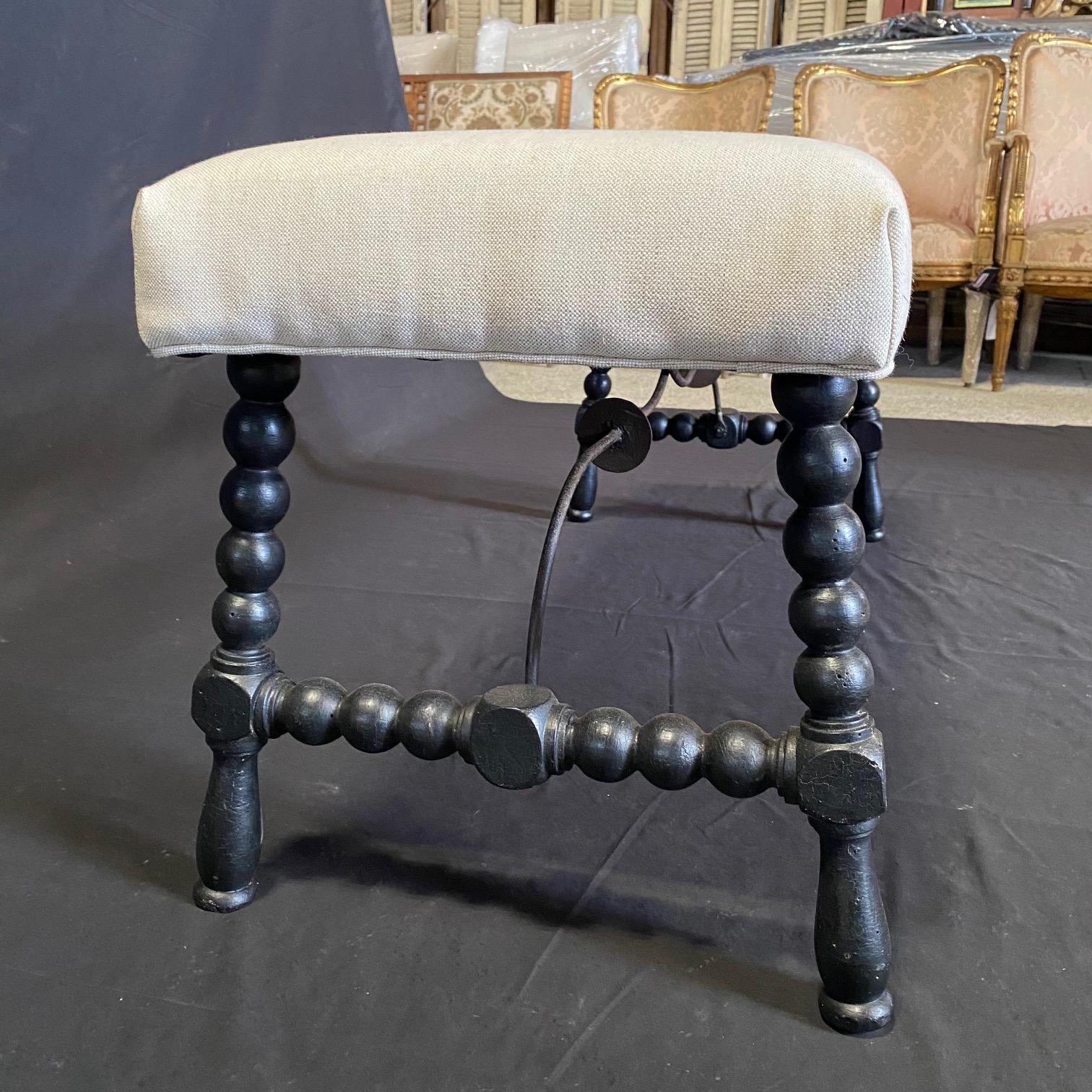 Exquisite ebony Spanish bench with turned wrought iron stretchers, a perfect addition to any contemporary or traditional setting.   Bench could also be used as an ottoman, and features a sleek design, combining new upholstery on the seat of the