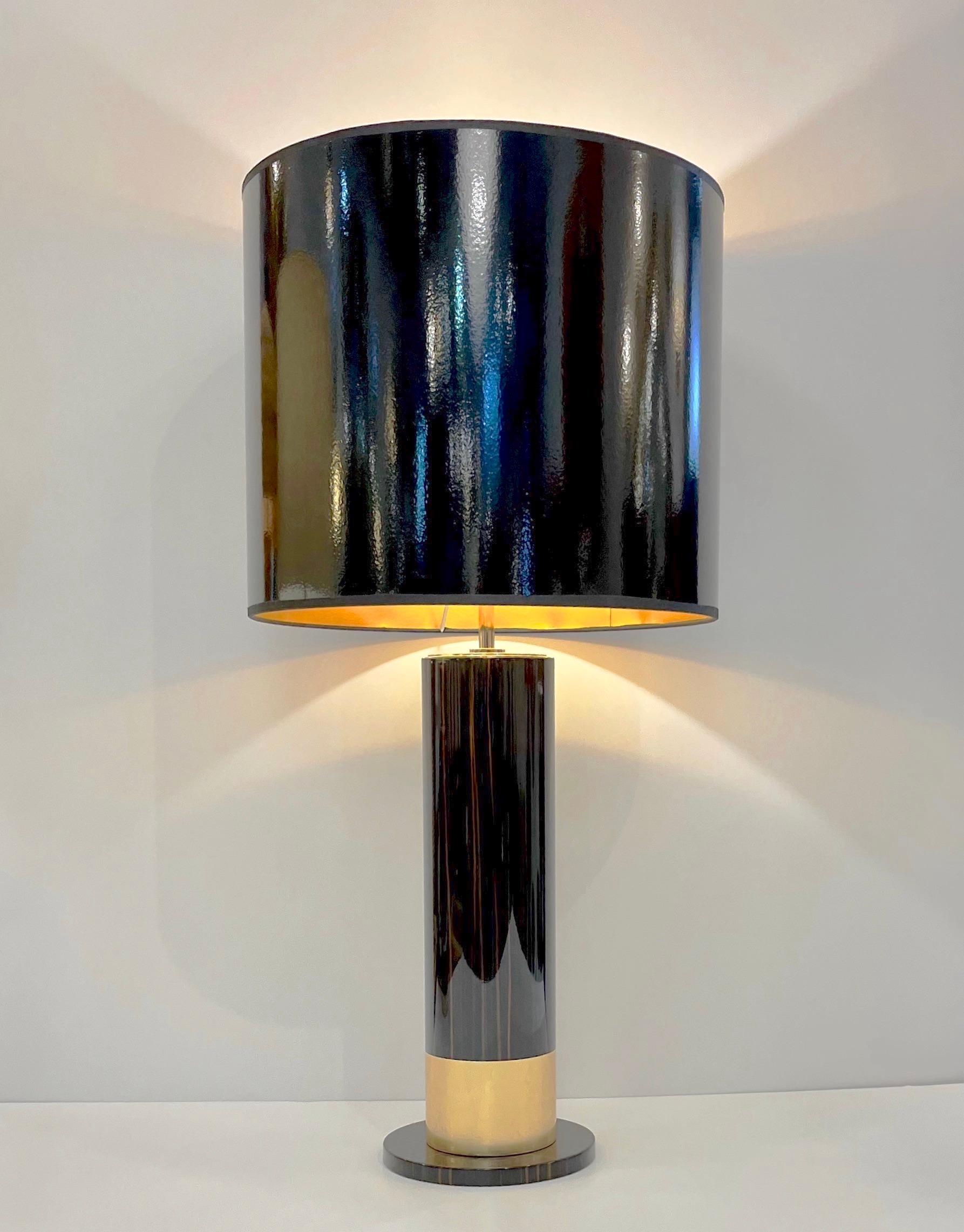 A contemporary pair of tall glamorous Hollywood regency design lamps, handmade in black and gold, high quality of execution with a sleek and modern mirror-like finish, the stem as an Art Deco column is highlighted with gold brown and black streak