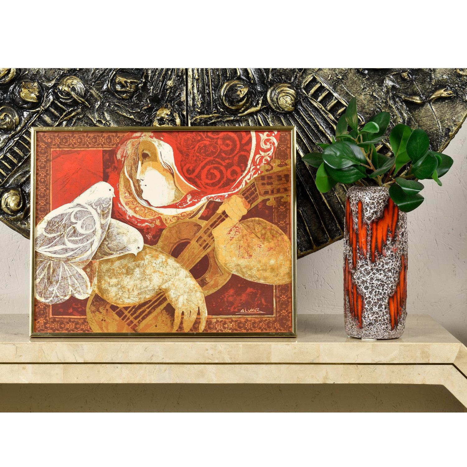 Beautifully framed lithograph of Sunol Alvar’s “The Guitarist and the Pigeons.” The print bears Alvar’s signature and is housed in a gold colored metal frame with a panel of acrylic protecting the art. The romantic image elegantly captures the