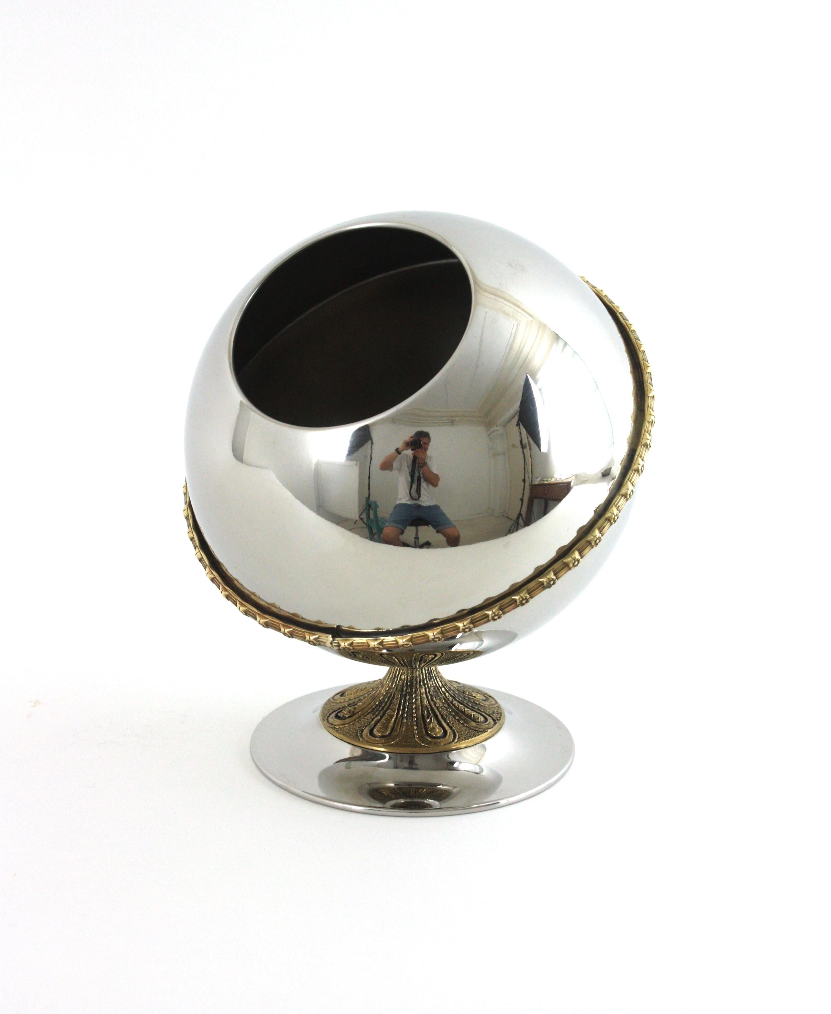 Seau à glace en forme de boule du milieu du siècle avec détails en bronze. 
Ce refroidisseur de vin sexy en acier inoxydable et en laiton comporte une boule posée sur une base avec des décorations de feuillage en laiton. À la manière de Valenti.