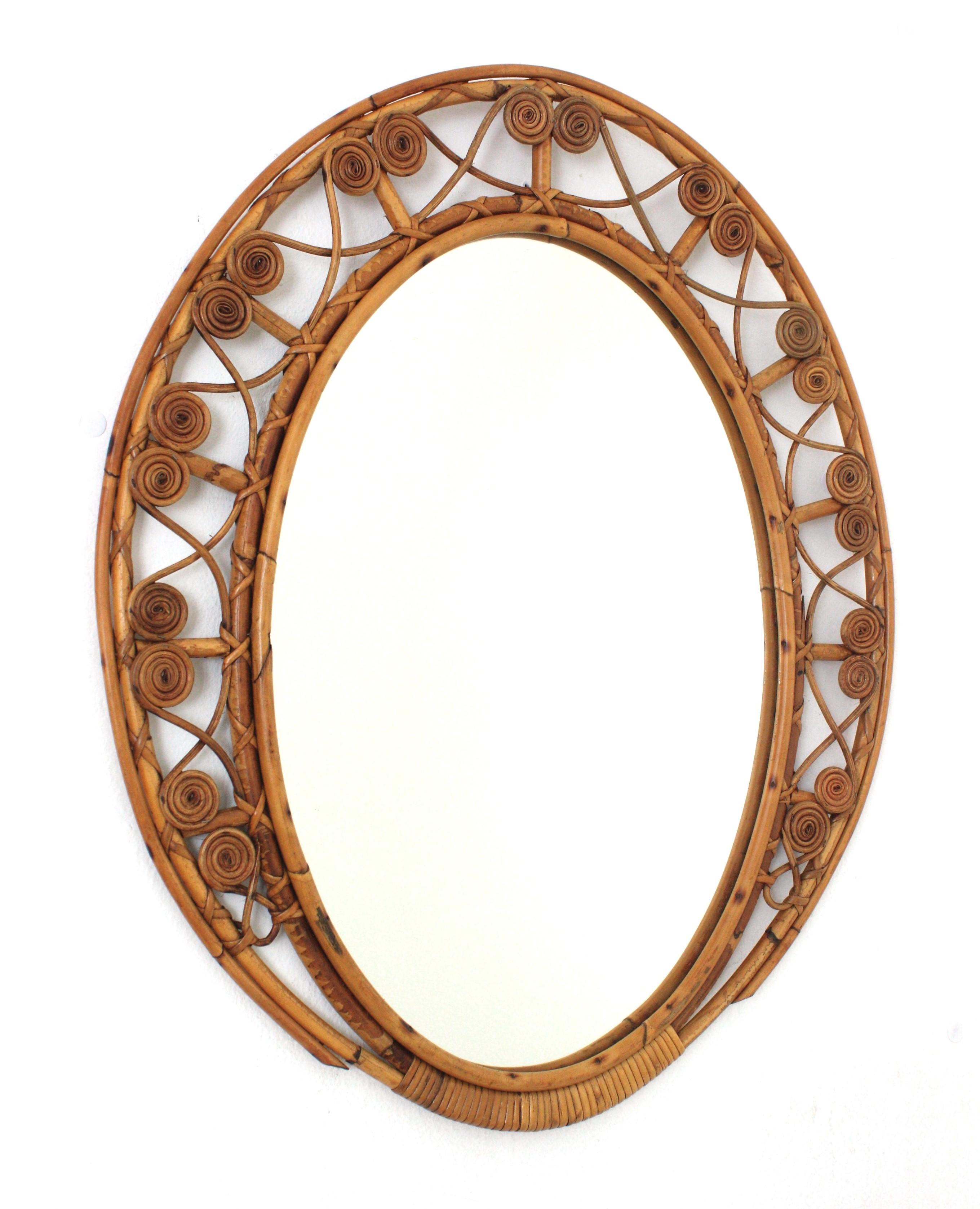 Midcentury rattan ovoid mirror with filigree details on the frame, 1950s-1960s
This lovely handcrafted mirror features an ovoid frame made of rattan canes. It has a wicker cane intricate with filigree scrolled decorations.
It has a big enough glass