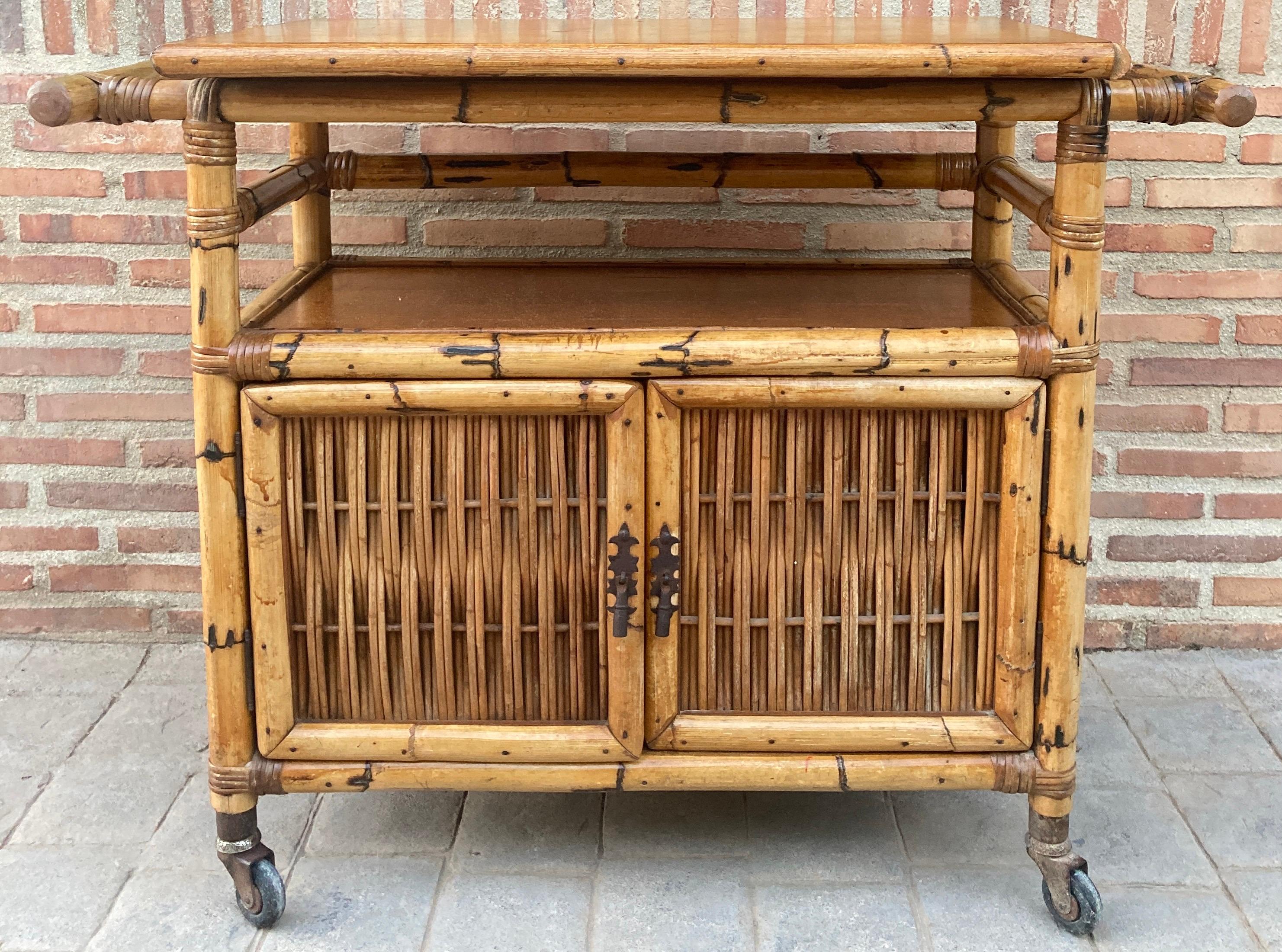 Beautiful Spanish bamboo bar cabinet from the 1950s with a cupboard door and a lower shelf with a bottle rack.
On its legs it has wheels as a bar cart.
Design period 1950 to 1959. 
Year 1950.
Production period 1950 to 1959. 
Style vintage,