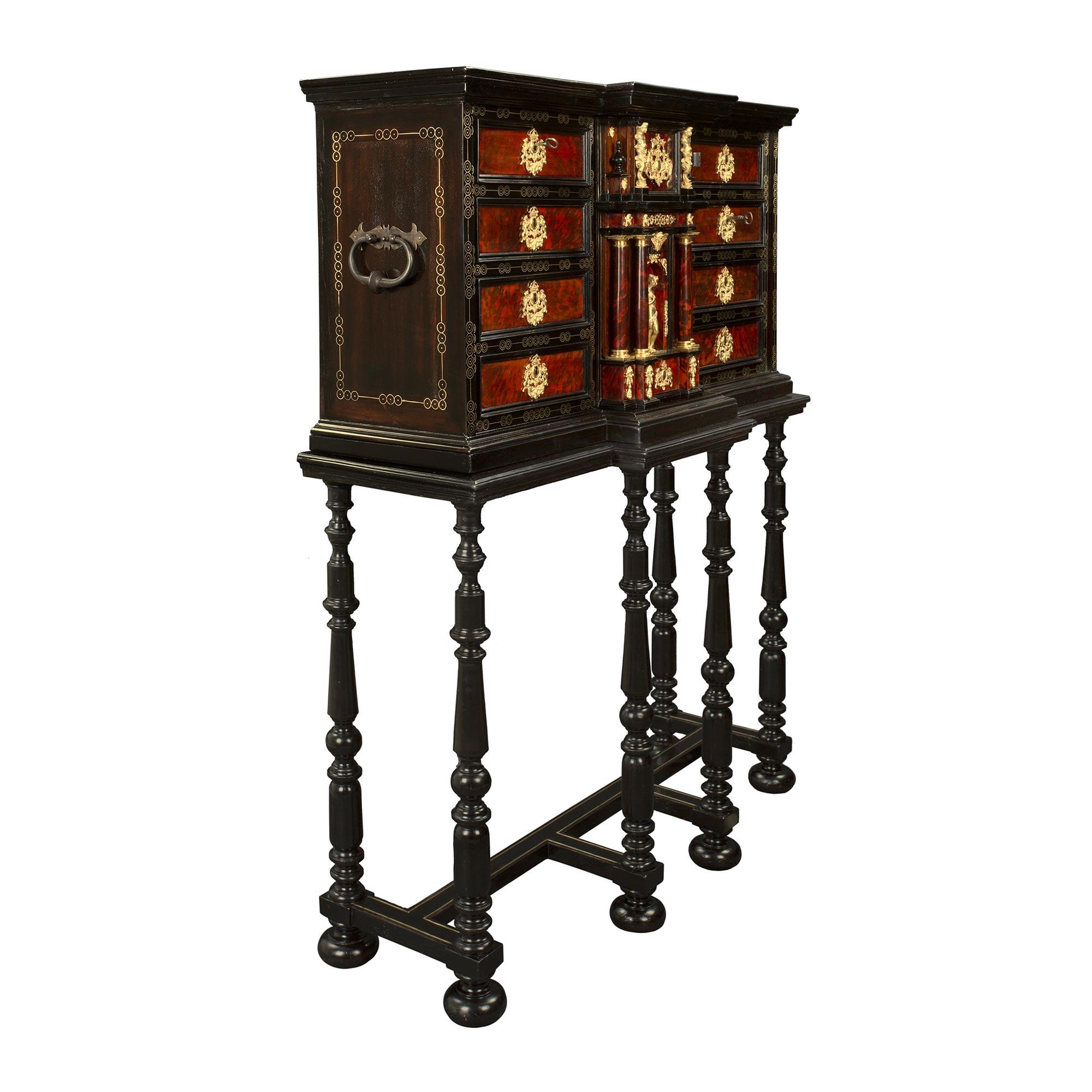 A spectacular and most decorative Spanish Baroque 18th century ebony, brass, gilt metal, iron and tortoise shell specimen cabinet on the original stand. The cabinet is raised by six elegant turned ebony legs with fine bun feet and a square stretcher