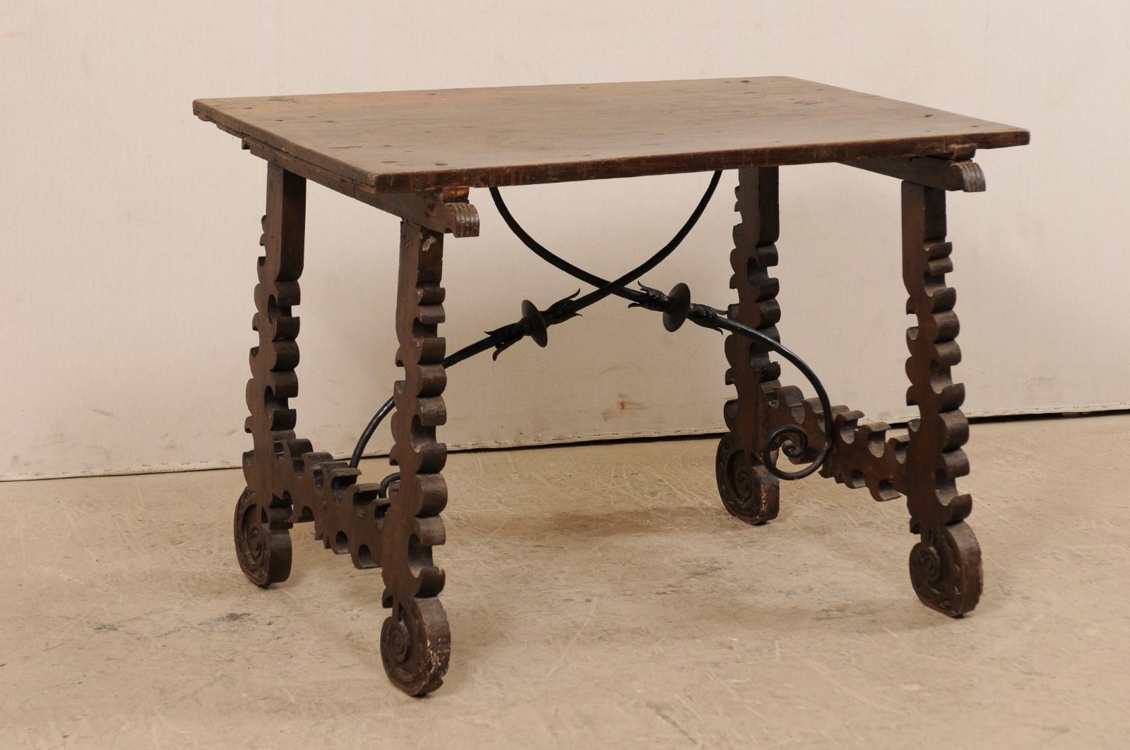 A Spanish baroque table with decorative forged-iron stretcher from the 18th century. This antique table from Spain features a rectangular-shaped top, which is raised upon a pair of fluidly-carved, lyre-shaped trestle styled legs at either end. The