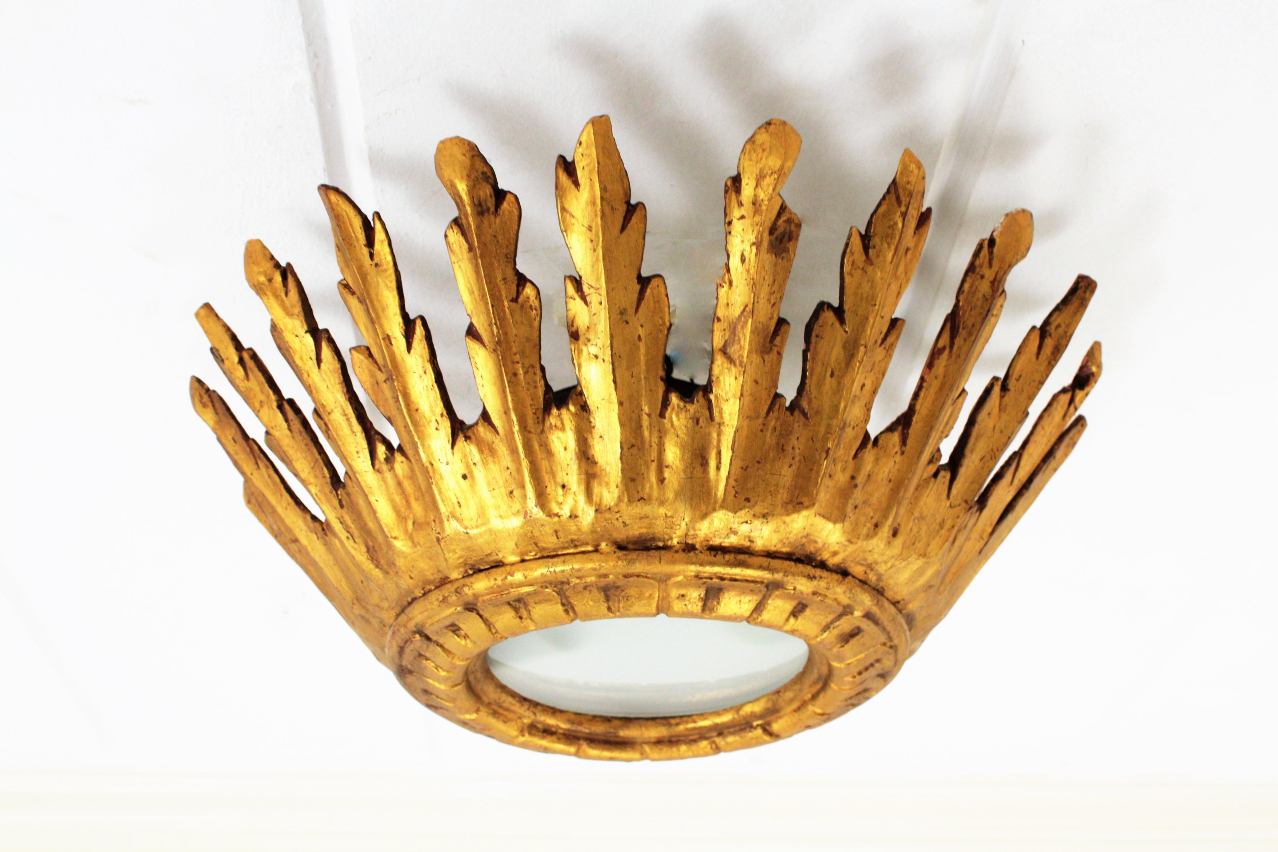 Amazing baroque style carved and gold leaf giltwood crown sunburst light fixture with frosted glass diffuser. Spain, 1930s-1940s.
This outstanding sunburst crown light fixture or flush mount can be used also as a chandelier hanging from a chain at