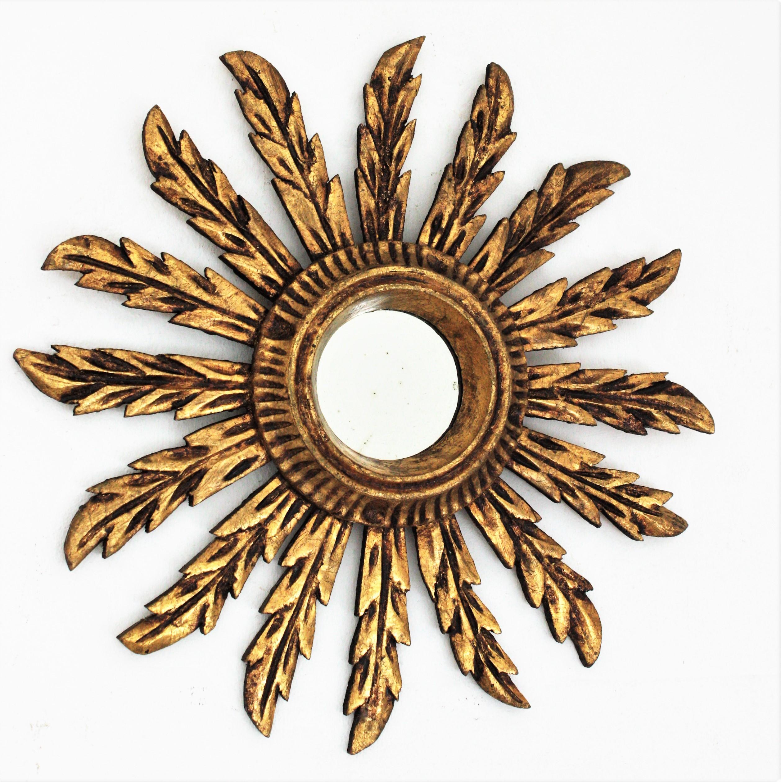 Early 20th century carved giltwood medium sized sunburst mirror in Baroque style.
Beautiful giltwood sunburst mirror with carved leafed frame comprised by 16 leaf rays gilded with gold leaf 
Carved wood covered with gesso and gold leaf finish.
