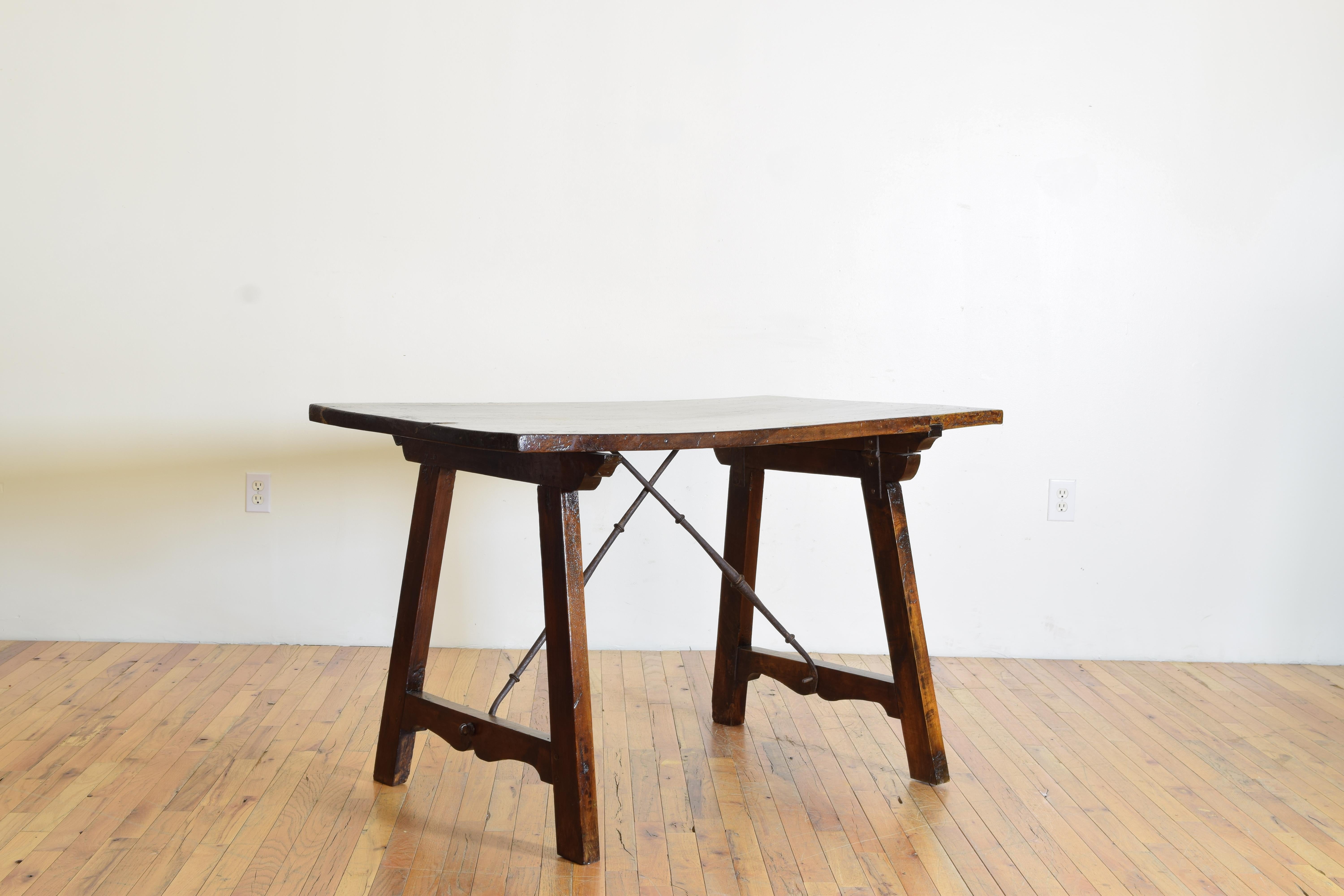 In its day a portable table these sometimes referred to as “guard room tables” have hinges atop the trestle supports and fold up when the iron stretchers are unscrewed, this table having a rectangular top with lovely dark patina and excellent grain,