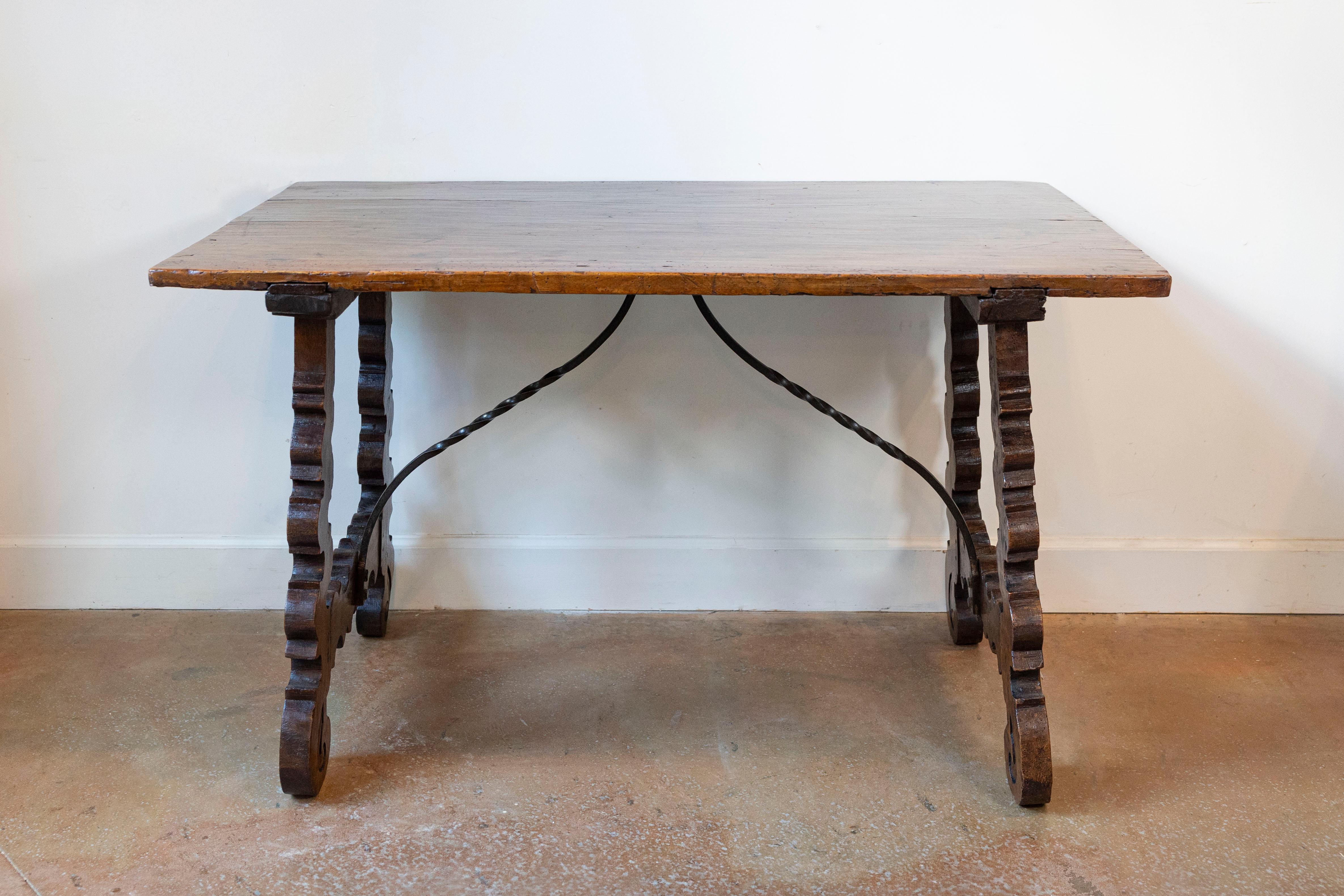A Spanish Baroque style Fratino walnut console table from the 19th century, with lyre-shaped base and iron stretchers. Created in Spain during the 19th century, this Fratino walnut console table features a simple rectangular top sitting above an
