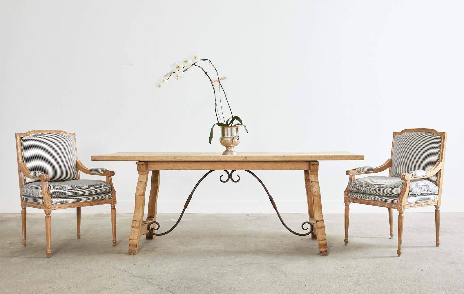 Impressive early 20th century Spanish baroque style library table or dining table crafted from oak. The table features an amazing bleached oak finish that truly brings out the classic design accented by the dark, patinated iron stretchers. The