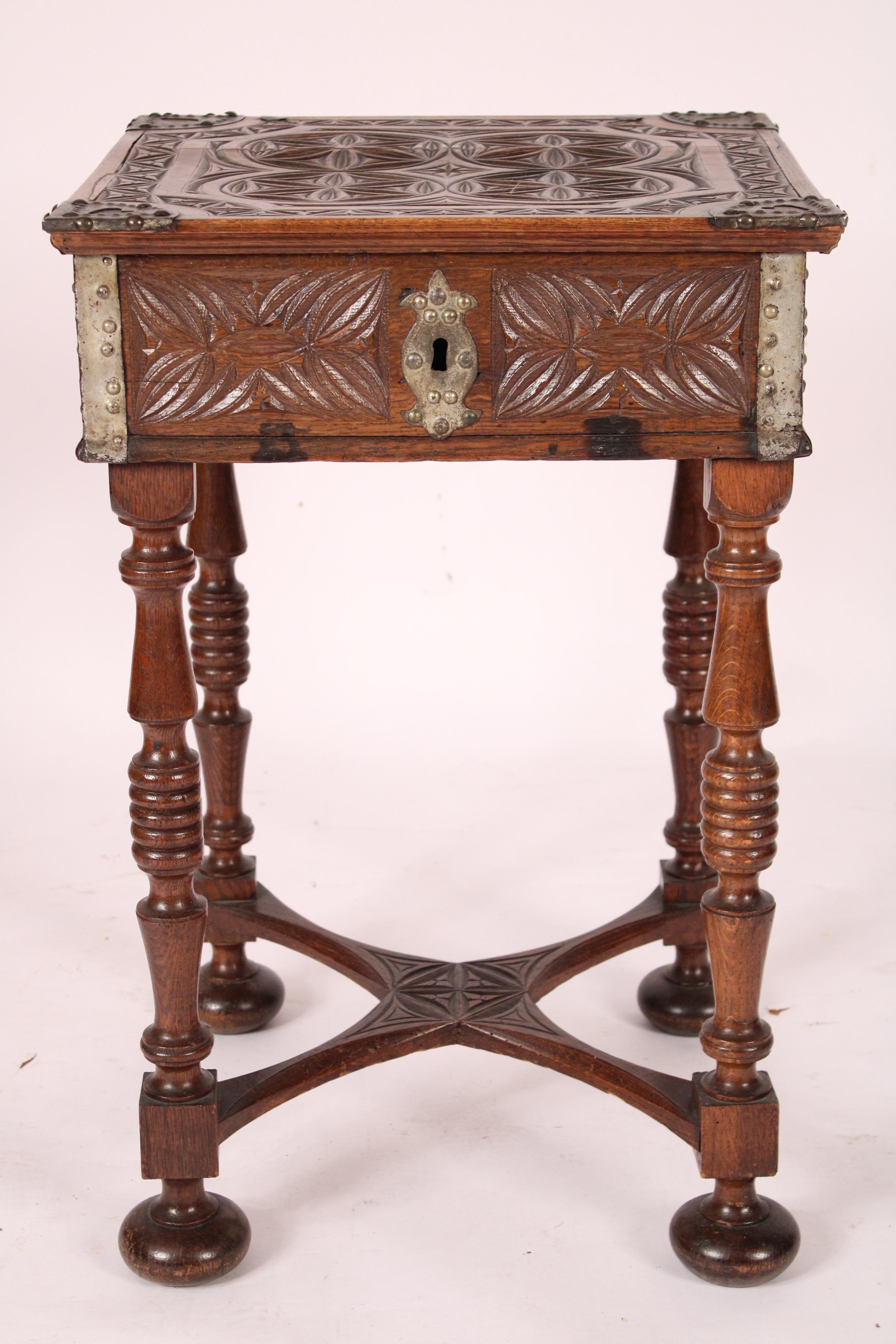 Spanish baroque style carved oak box, 19th century, resting on a circa 1930's oak stand. The hinged box with carved top and tole mounts on 4 corners, the front and sides of the box are carved with iron handles on the sides, the stand with turned