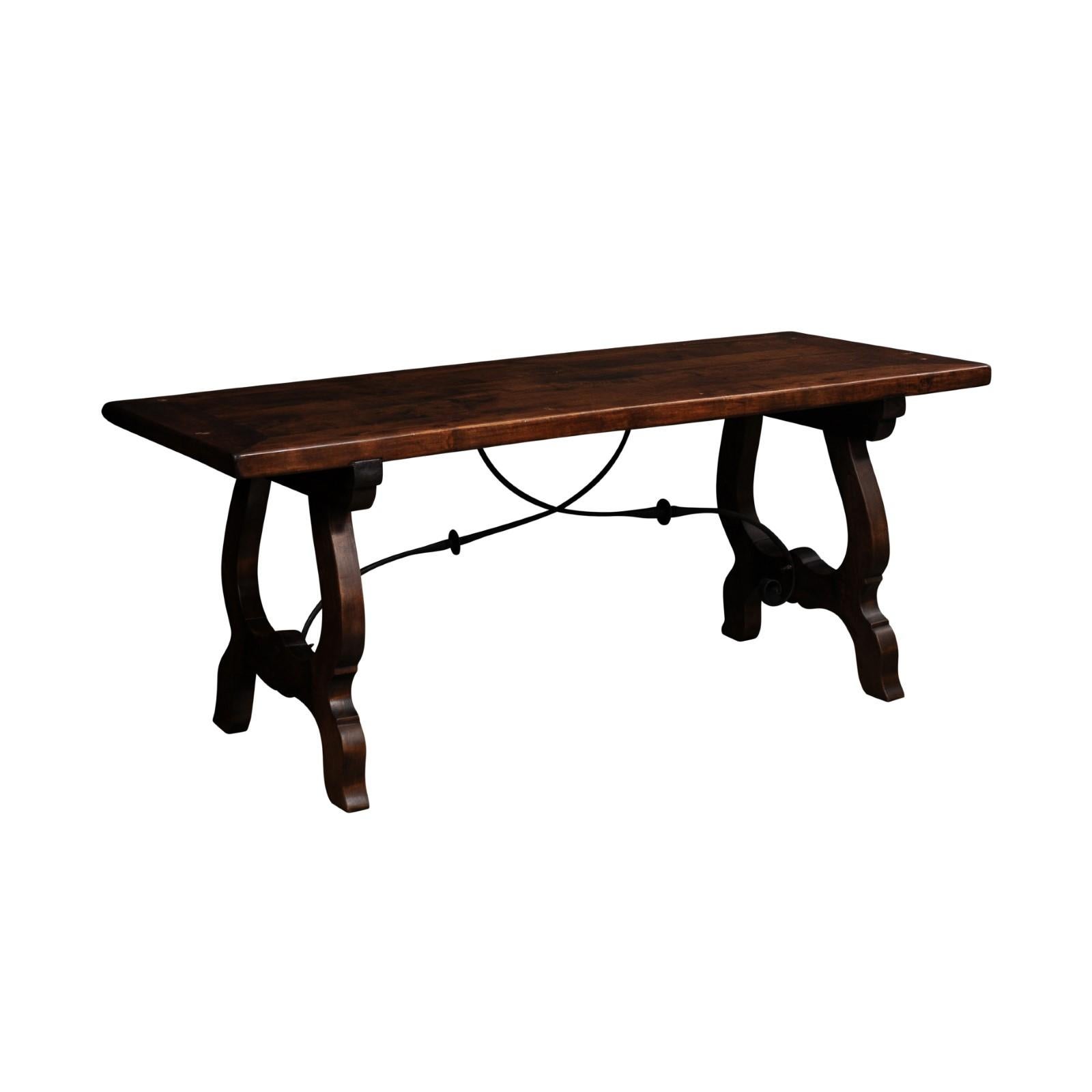 A Spanish Baroque style walnut fratino table with carved lyre shaped base and iron stretcher. Immerse yourself in the opulent world of Spanish Baroque style with this exquisite walnut fratino table, a piece that masterfully combines the drama and
