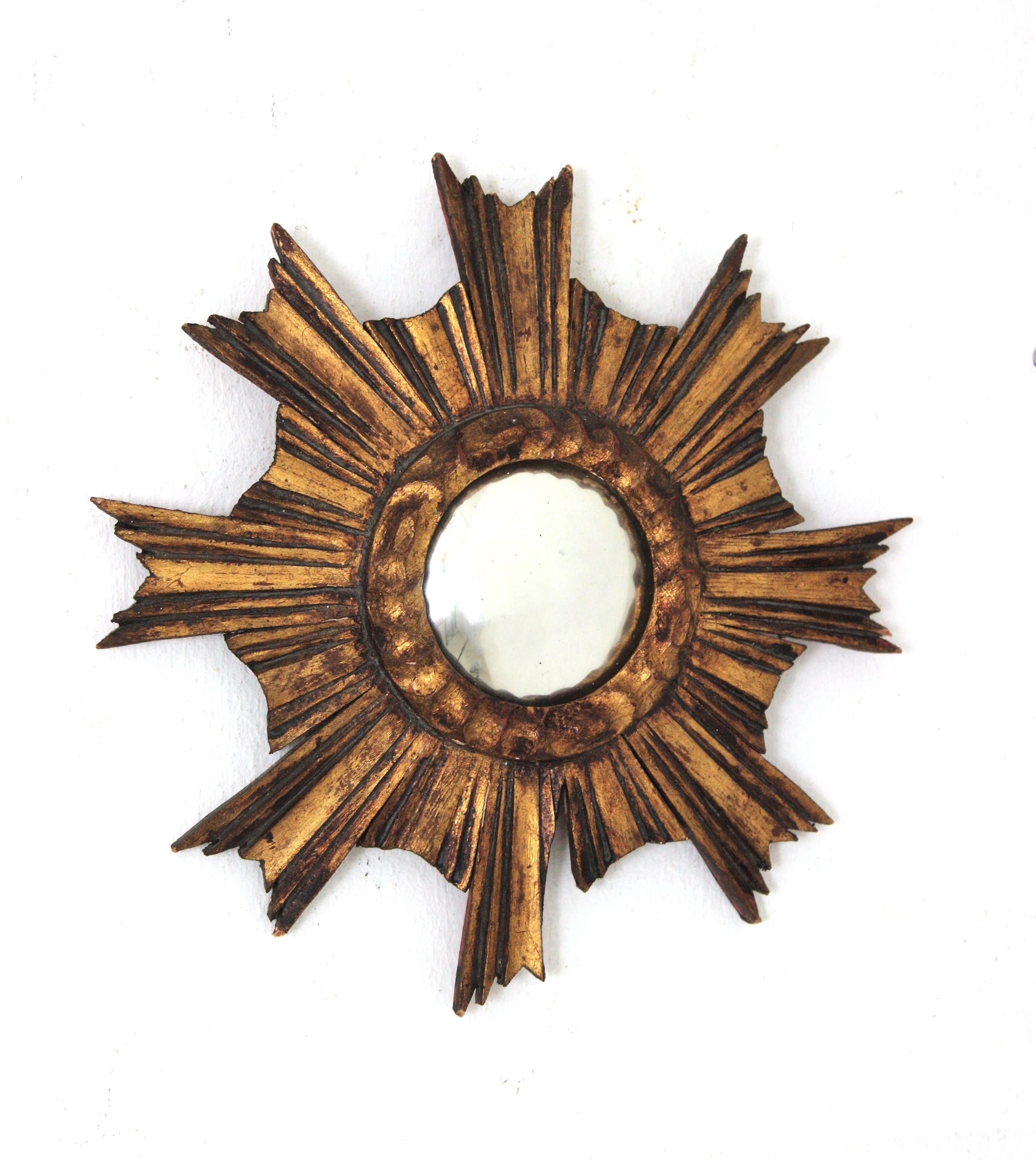 Wood Carved gold leaf gilded convex sunburst mirror in unusual mini size. Spain, 1930s-1940s.
This gorgeous miniature sunburst mirror has a frame comprised by carved rays in different sizes and convex glass. Finished in gold leaf gilding. This piece