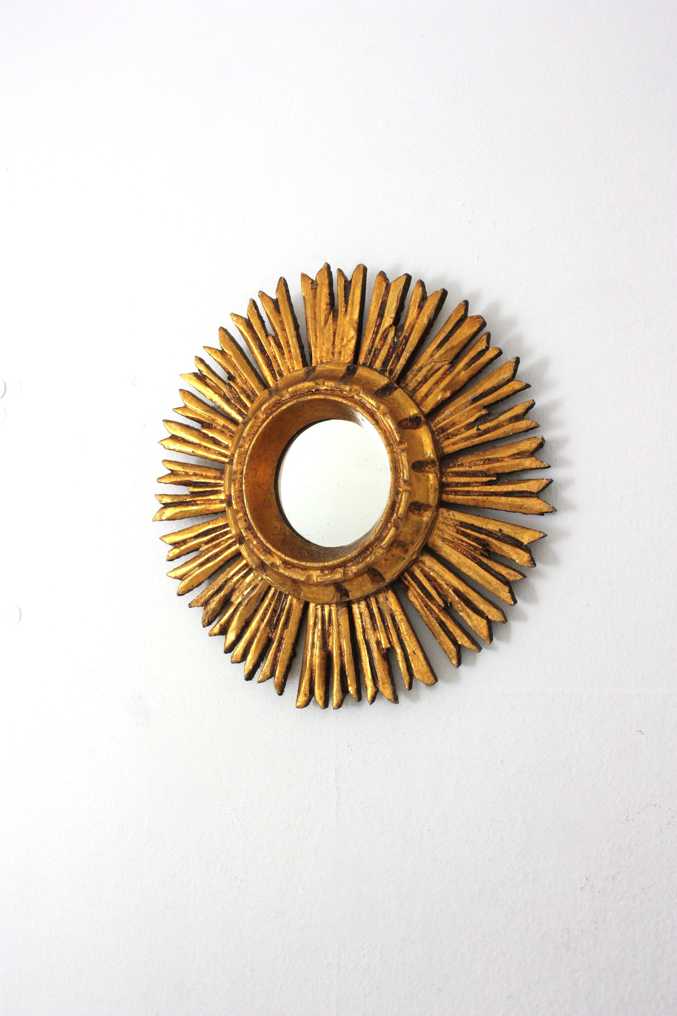 Mini sized carved giltwood convex sunburst mirror, Spain,  1940s
This lovely petite giltwood sunburst mirror with carved frame has a terrific patina and shows it original gold leaf gilding.
Place it alone or as a part of a sunburst mirrors wall